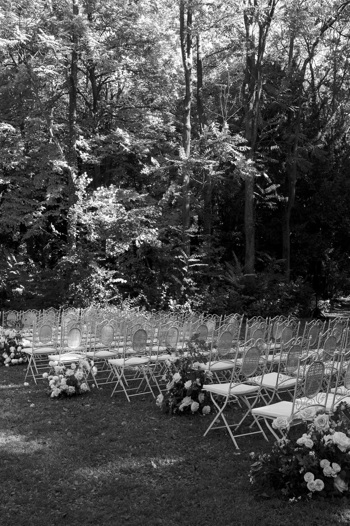 Outdoor wedding ceremony setup with curved seating arrangement in wooded garden venue