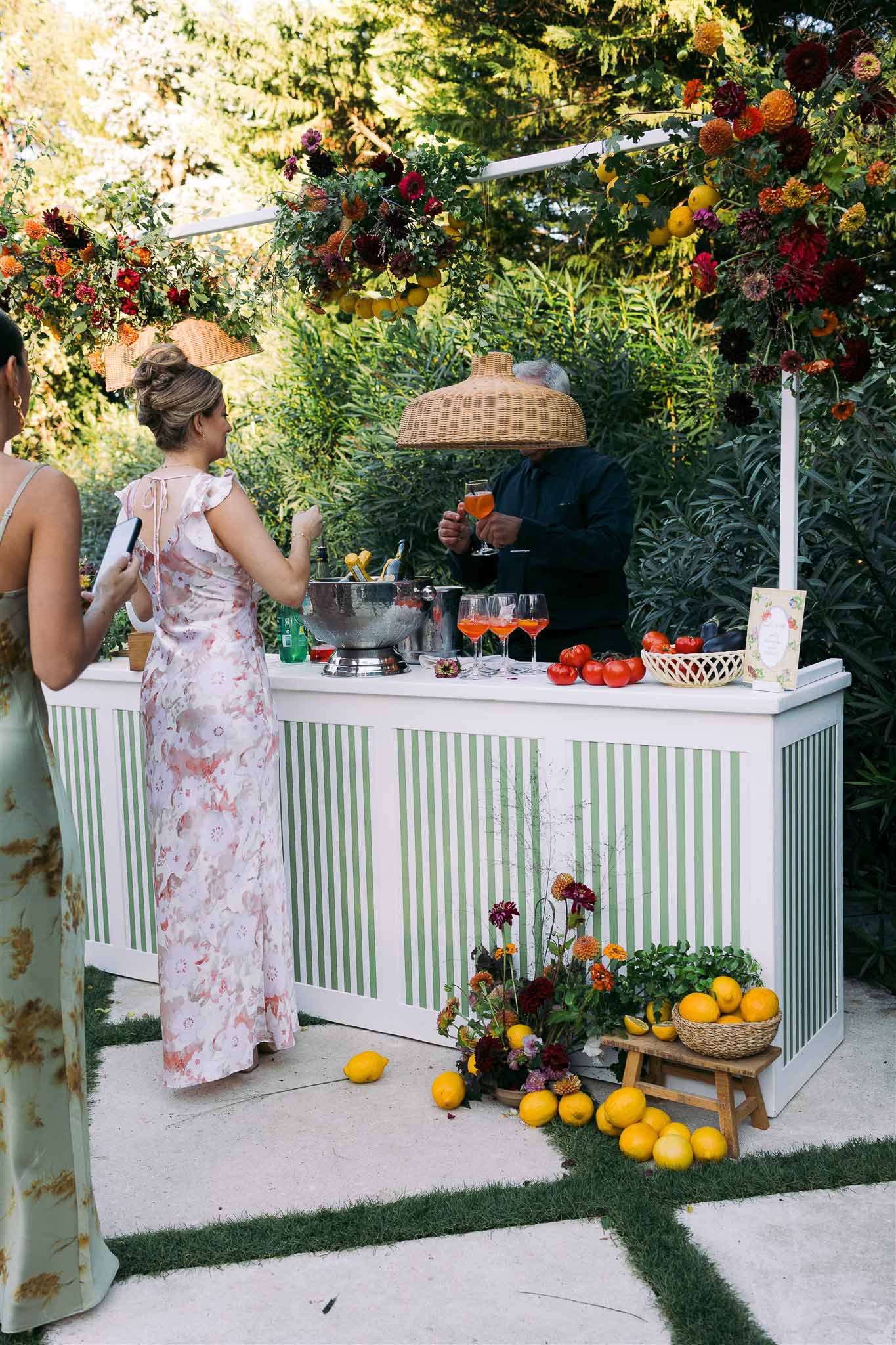 Cocktail hour with custom bar station and floral pergola in outdoor garden wedding setting