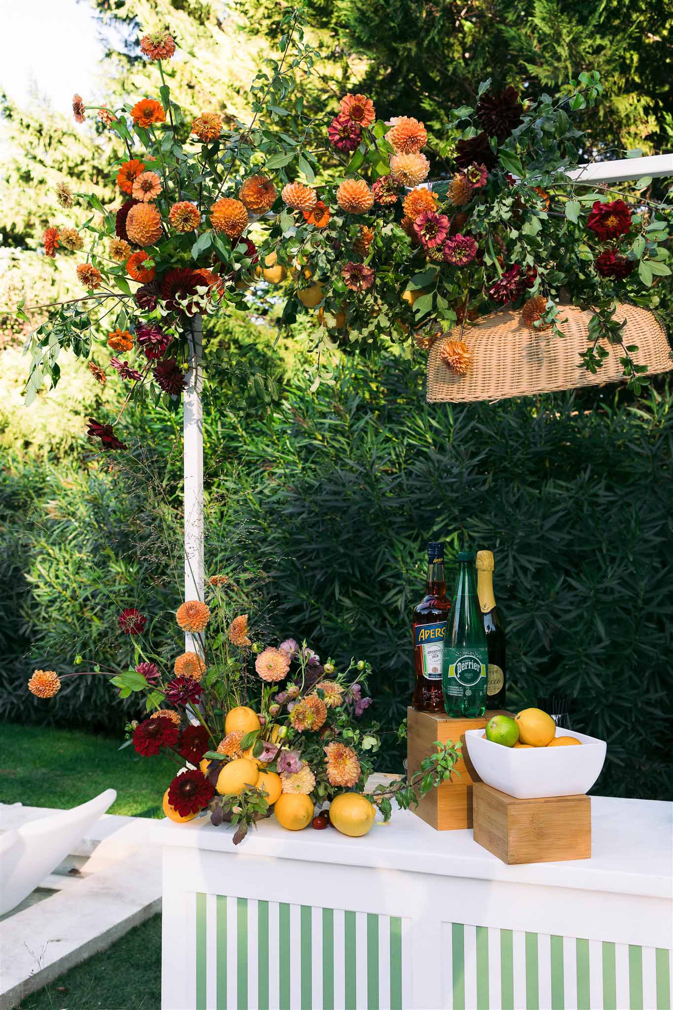 Decorated cocktail station with coral dahlias and citrus fruits in garden setting