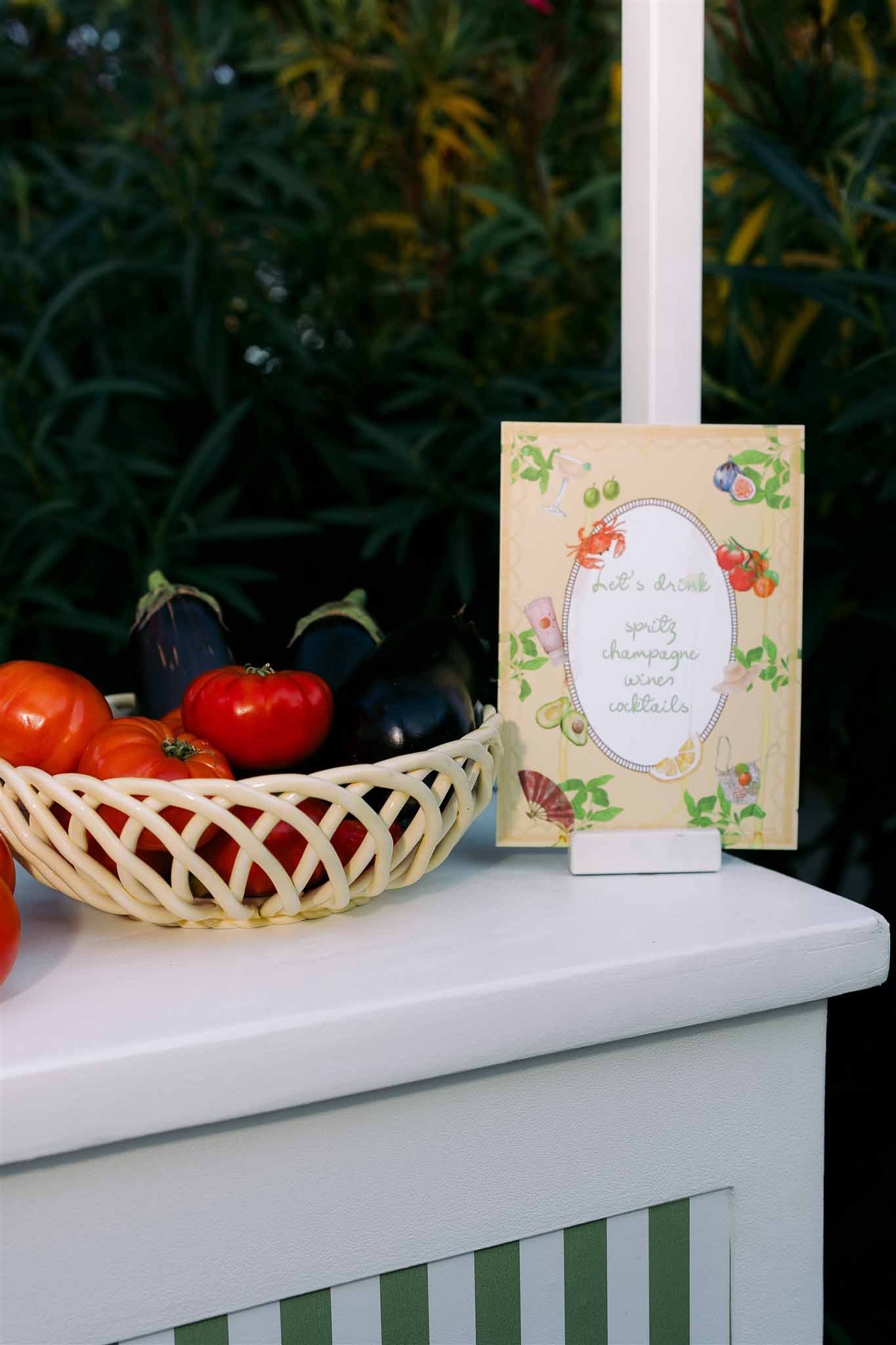 Hand-painted menu card with watercolor illustrations and fresh vegetables display at garden wedding reception