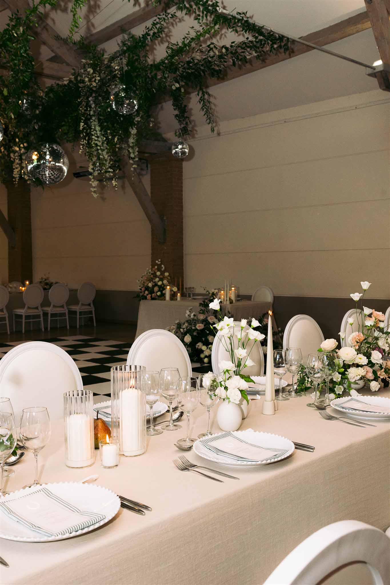 Reception dining setup with floral centerpieces and candles in elegant indoor ballroom