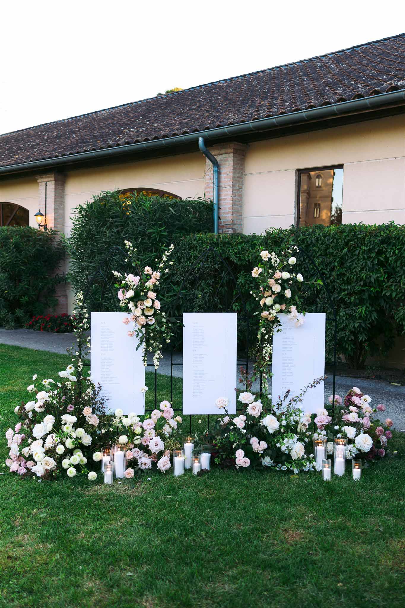 Wedding seating chart display with floral arrangements and candles at European-style venue