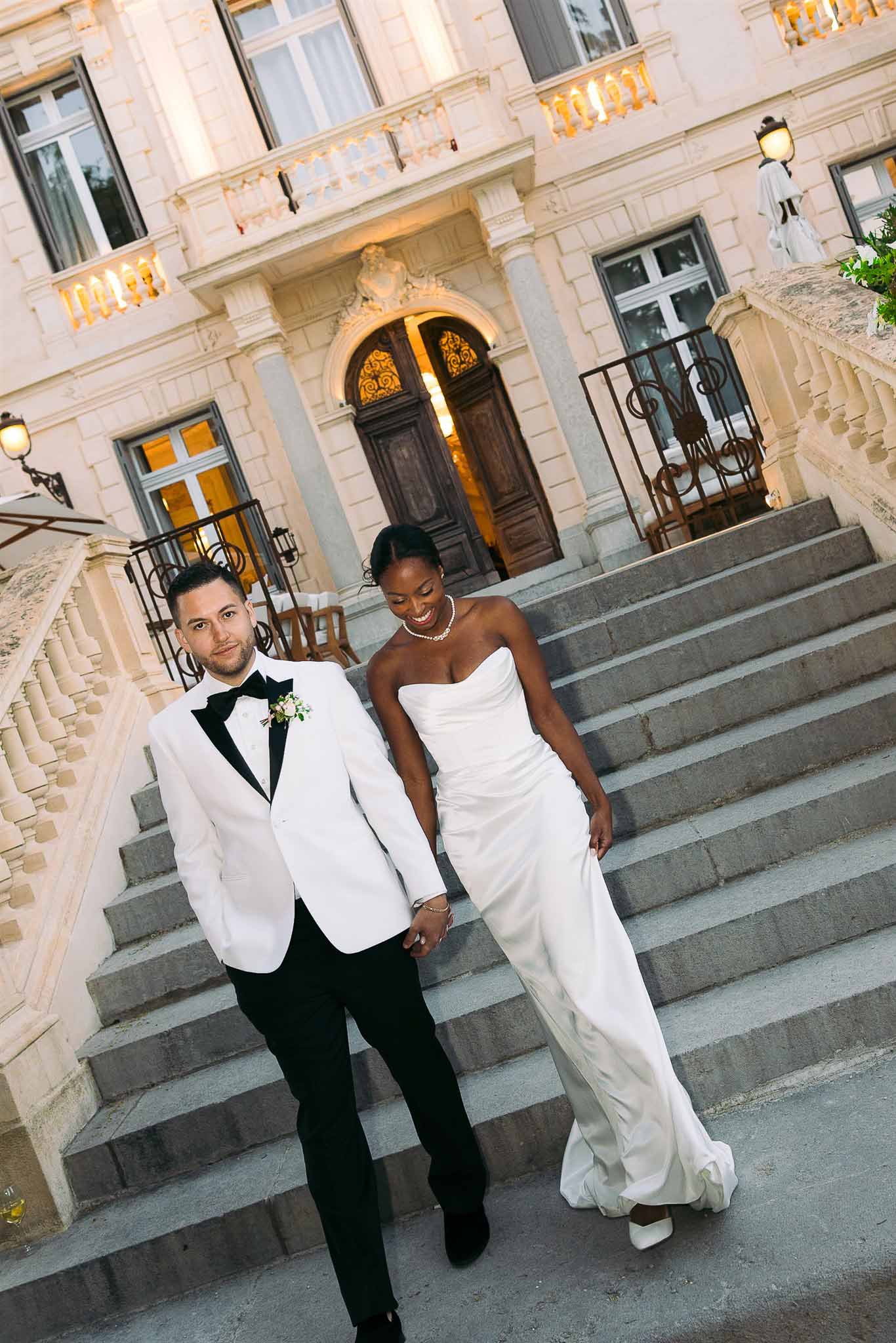 Bride and groom descending stone staircase at classical Parisian mansion