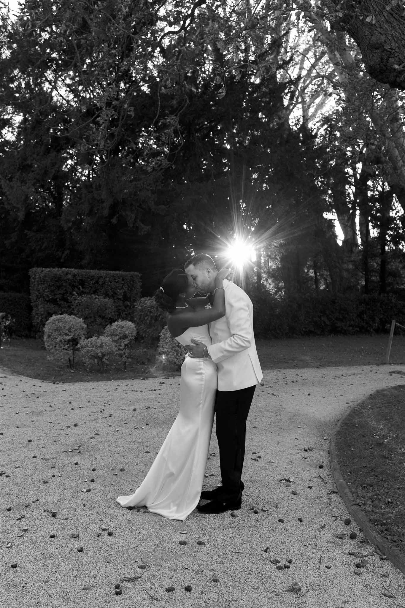 Bride and groom embracing in formal garden during golden hour portrait session