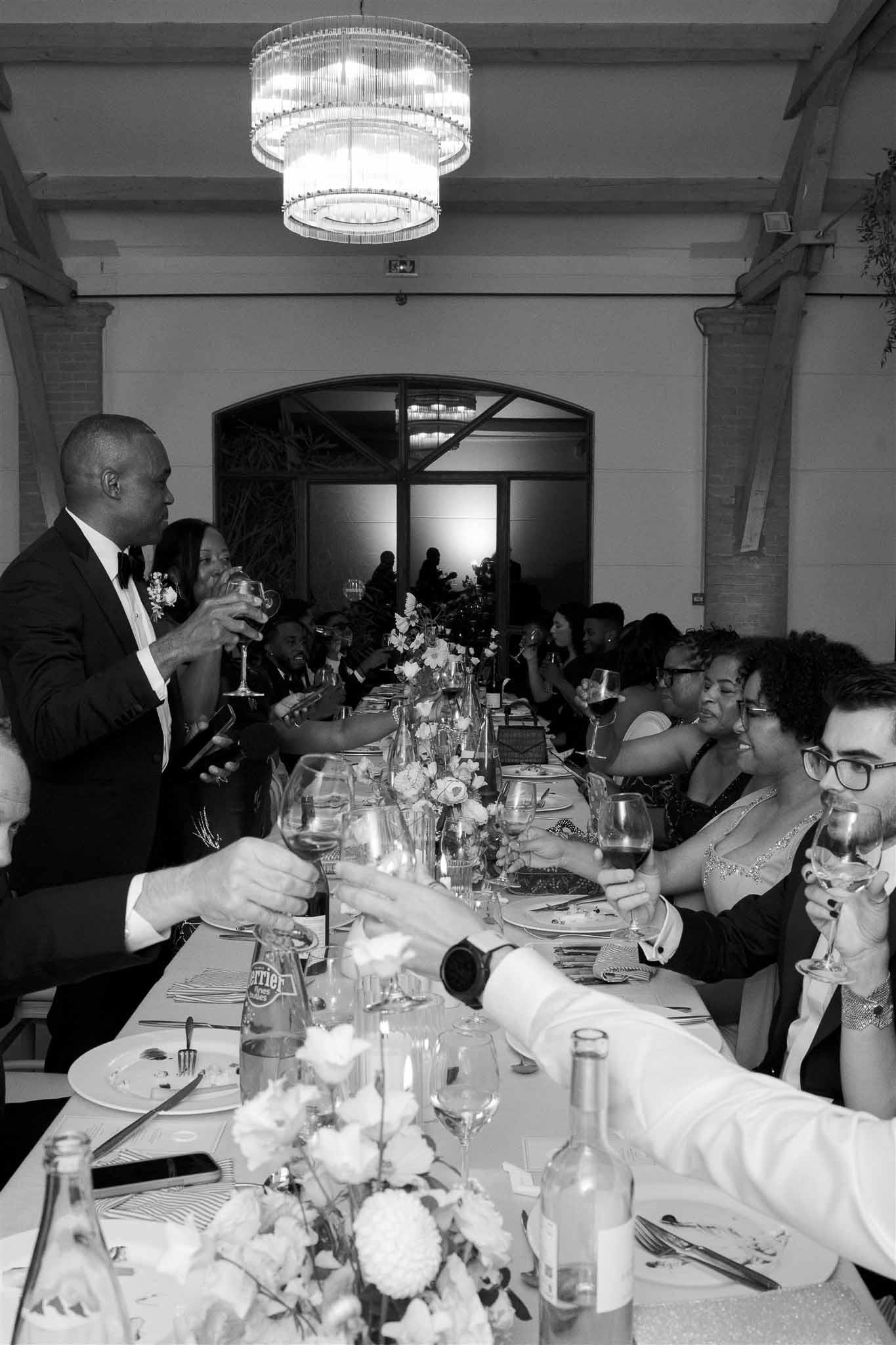 Wedding reception speech in modern ballroom with guests seated at long banquet table
