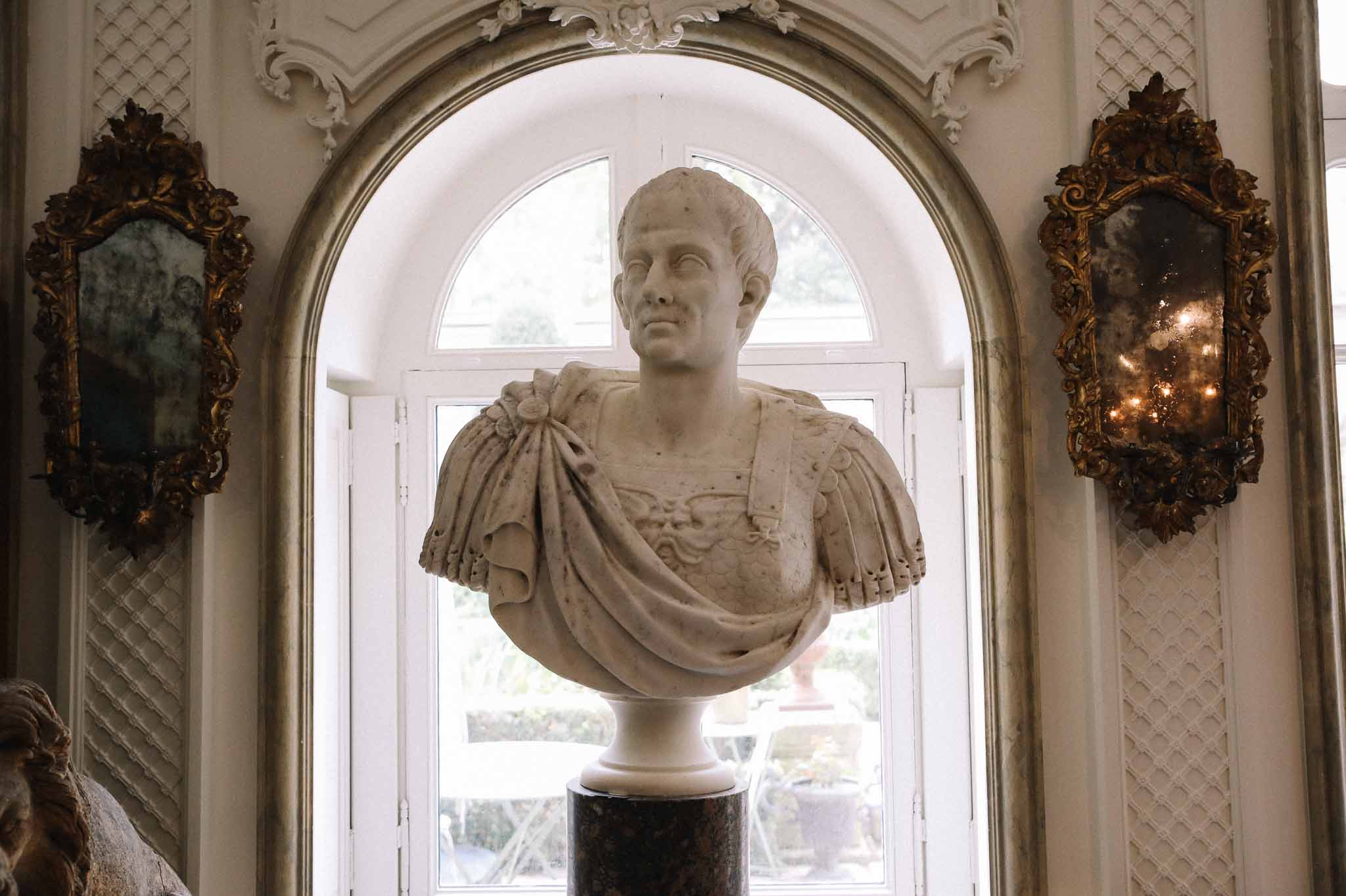 Classical stone bust in ornate arched niche with Baroque mirrors in elegant period venue interior