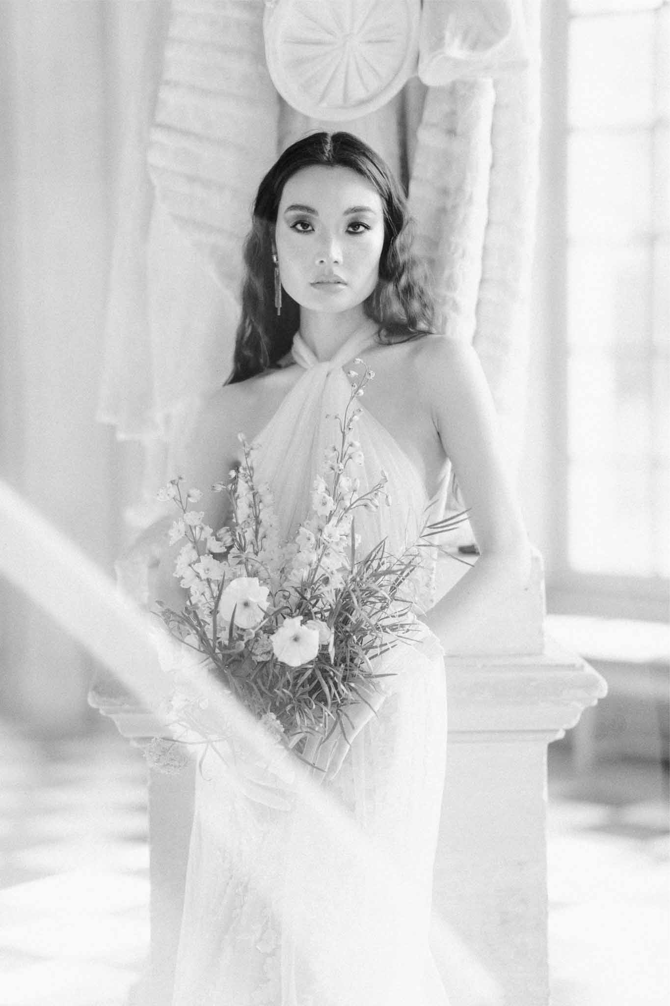 Black and white bridal portrait with classical columns and draped curtains in elegant indoor setting