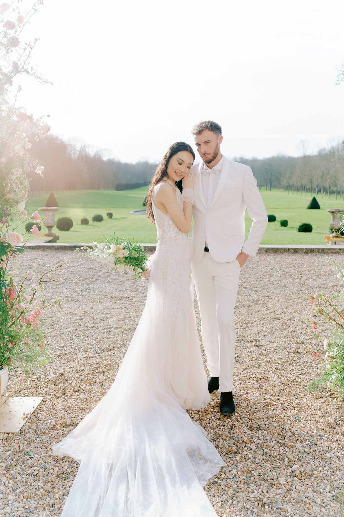 Bride and groom portrait session on gravel driveway at formal estate with manicured gardens