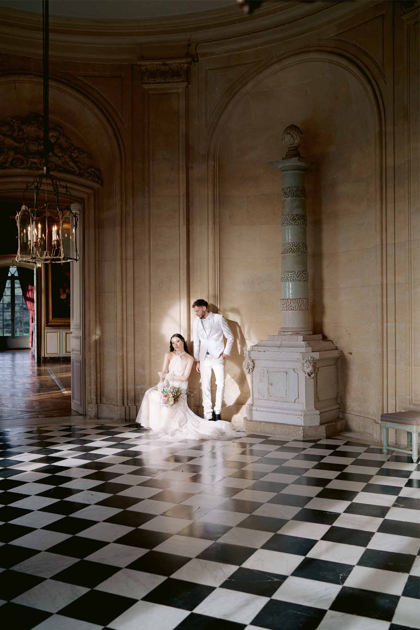 Bride and groom posing together in grand classical interior with arched ceilings and diamond pattern floor