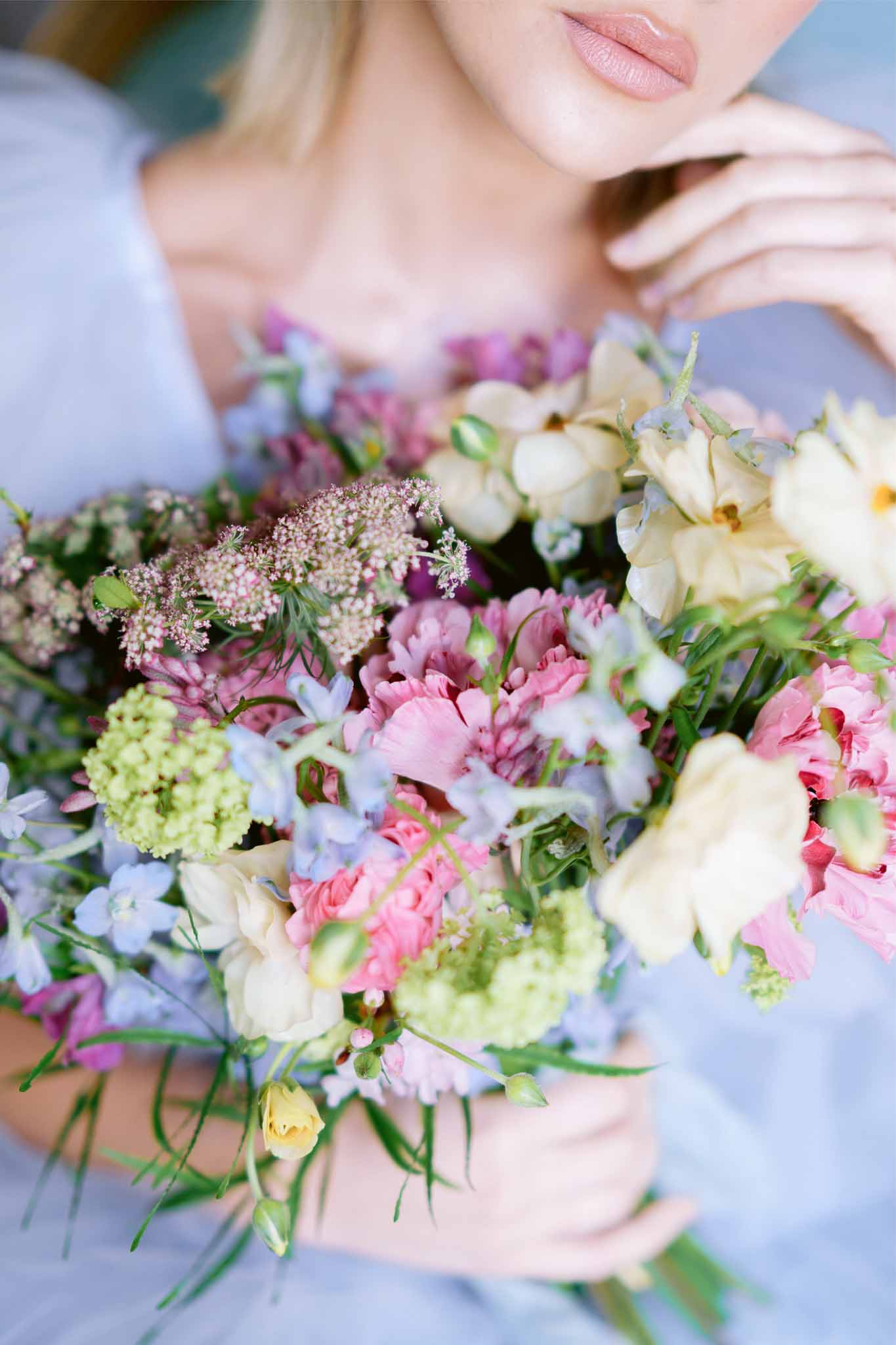 Bride holding pastel garden-style bouquet with cream roses and pink carnations in close-up detail shot