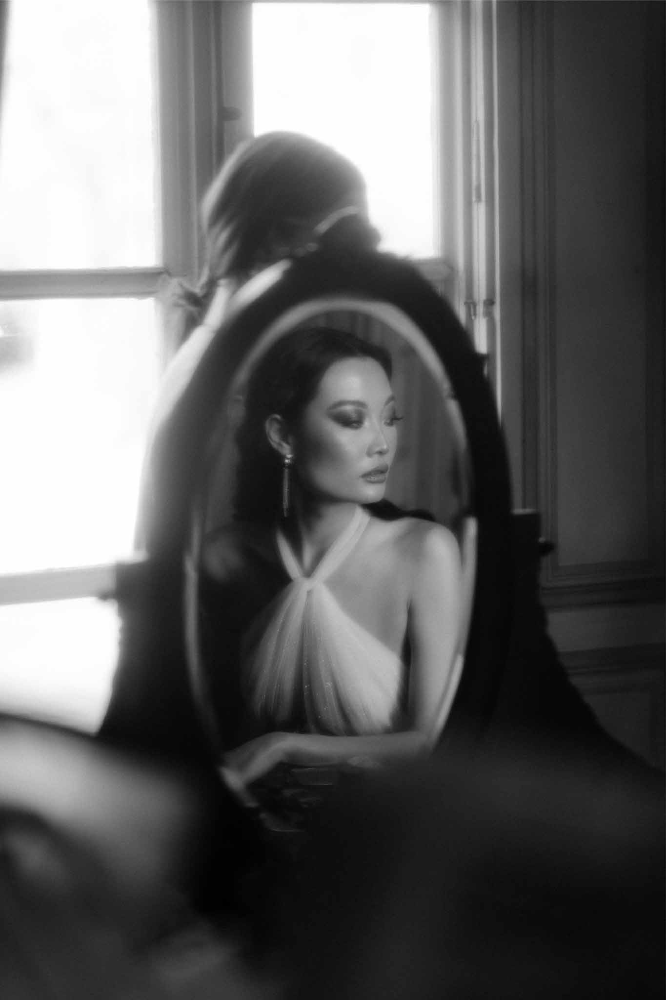 Bride in wedding dress and veil during preparation indoors by window