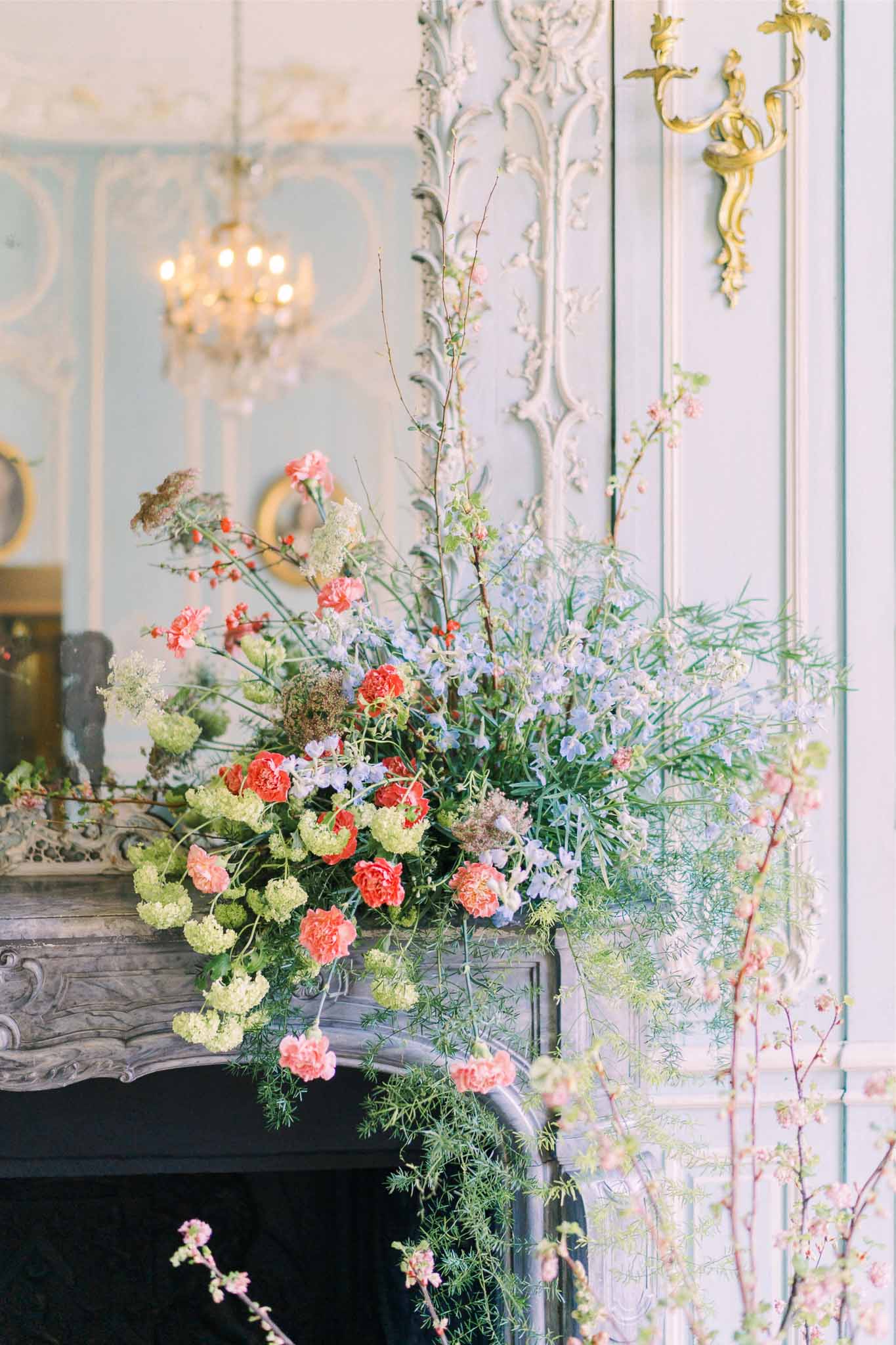 Coral and cream floral arrangement on ornate fireplace mantel in classical reception venue
