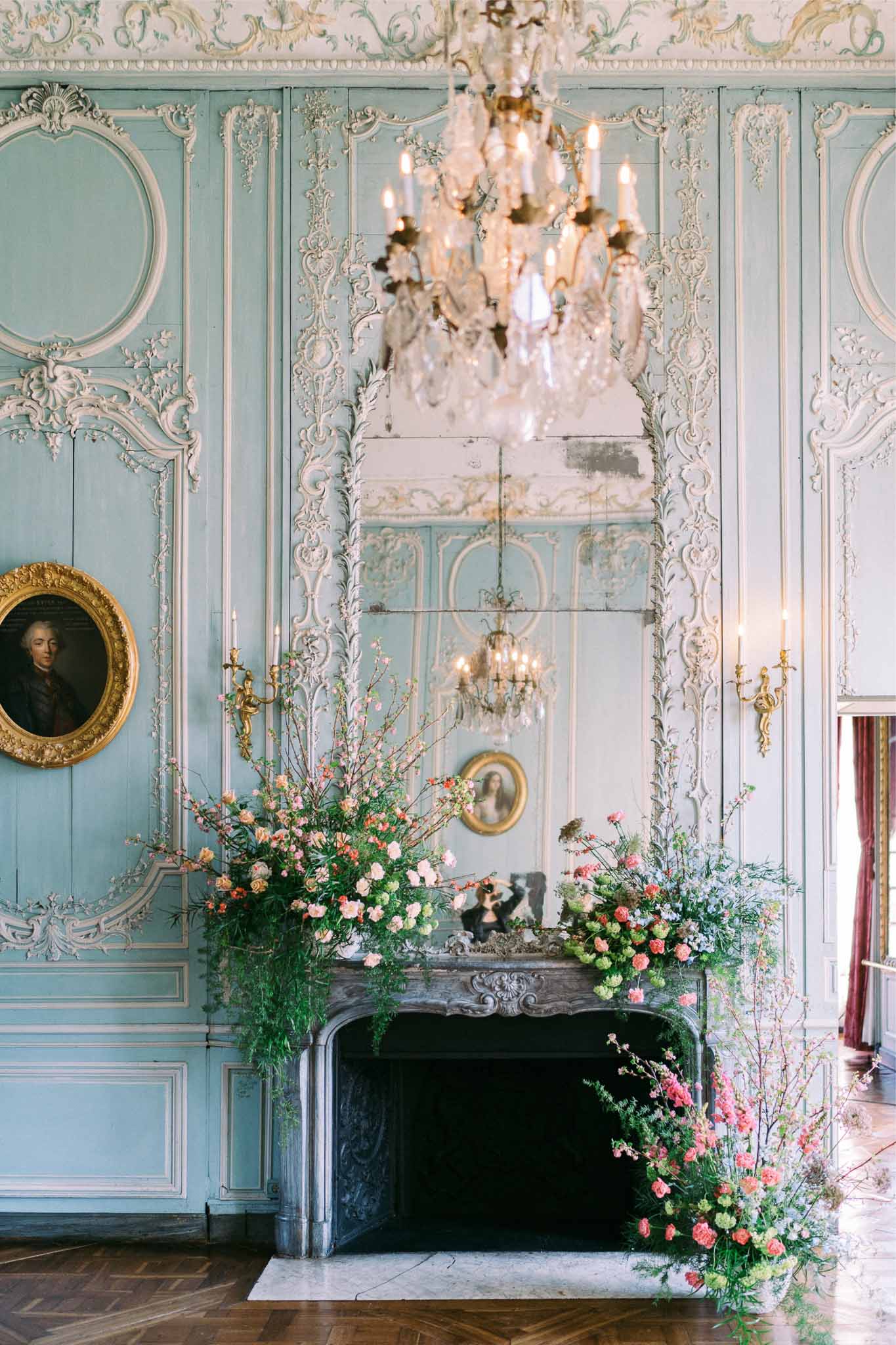 Ornate fireplace mantel with blush floral arrangements and candles in historic reception venue