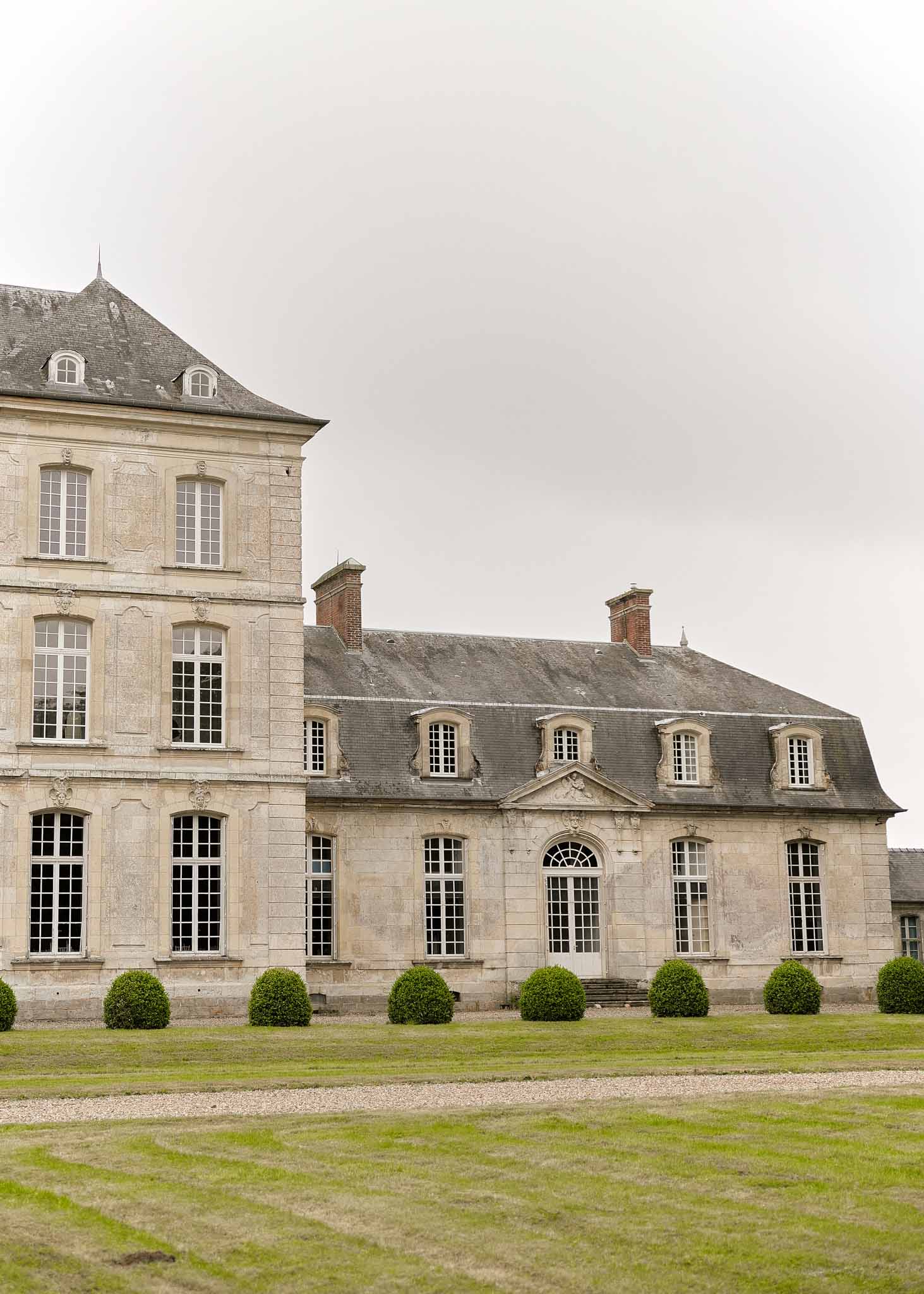 Classical French château with mansard roof and formal boxwood gardens at luxury wedding venue