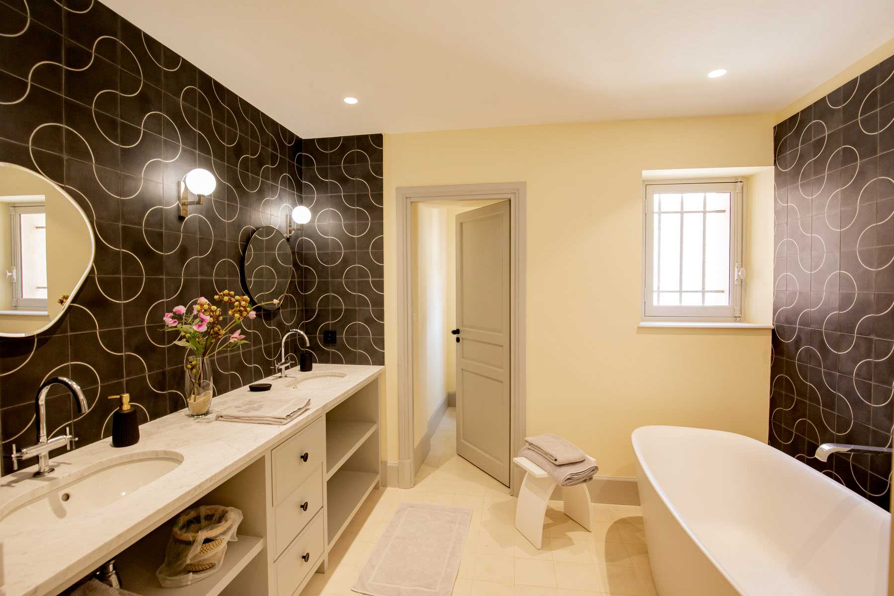 Bridal suite bathroom with freestanding bathtub, double vanity, charcoal accent tiles, and globe sconces