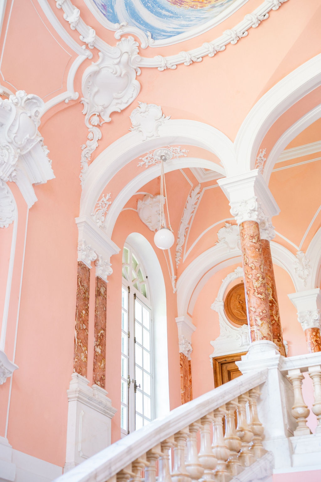 Ornate pink salon with stucco ceilings and marble columns at Domaine Rocabella, French Riviera
