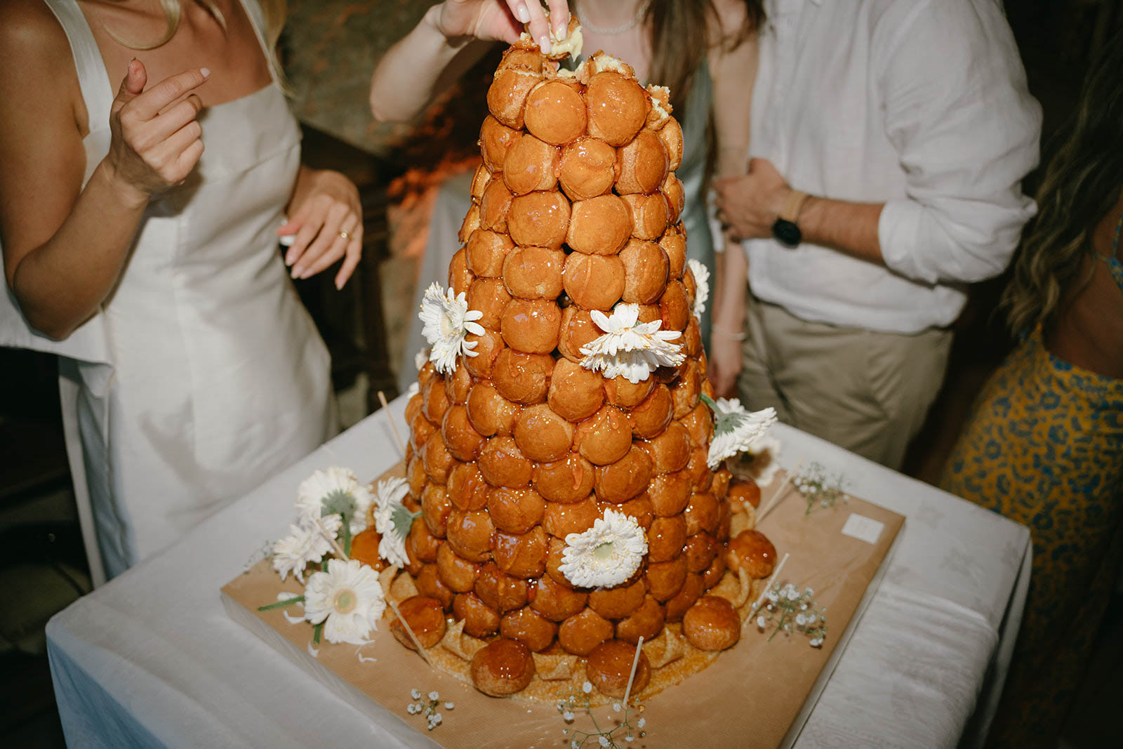 Bride and groom cutting croquembouche tower during wedding reception with guests watching