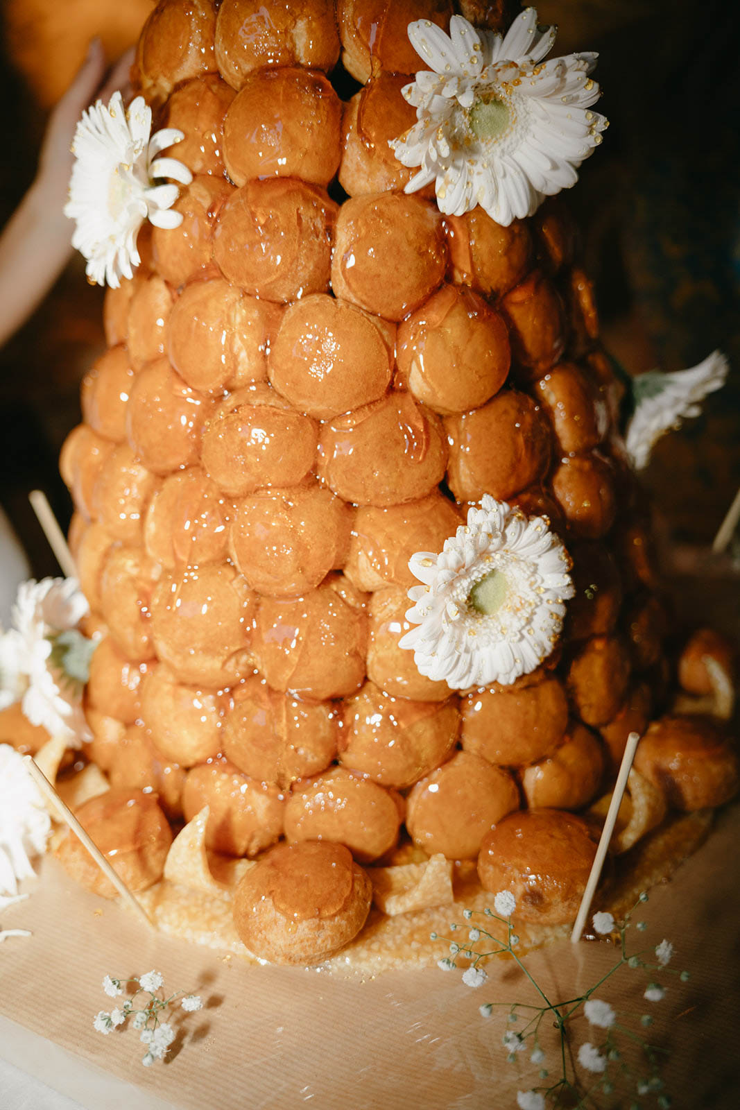 Croquembouche wedding dessert with white gerbera daisies and baby's breath on cream surface