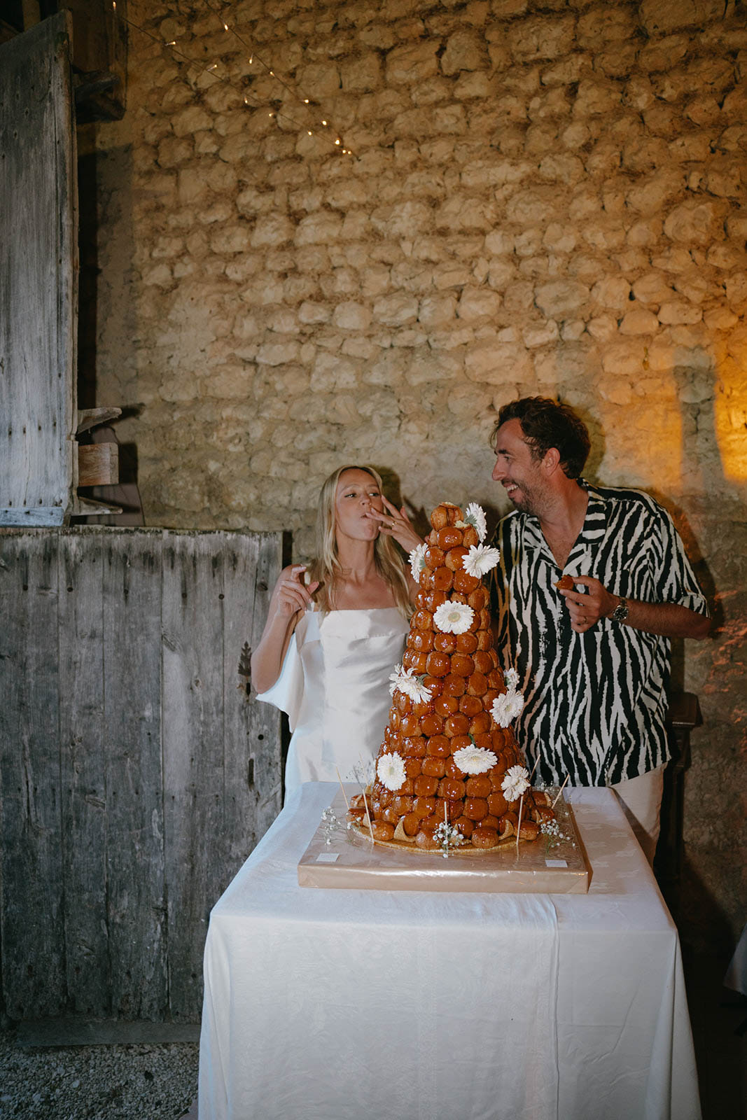 Bride and groom cutting croquembouche wedding cake at intimate indoor reception