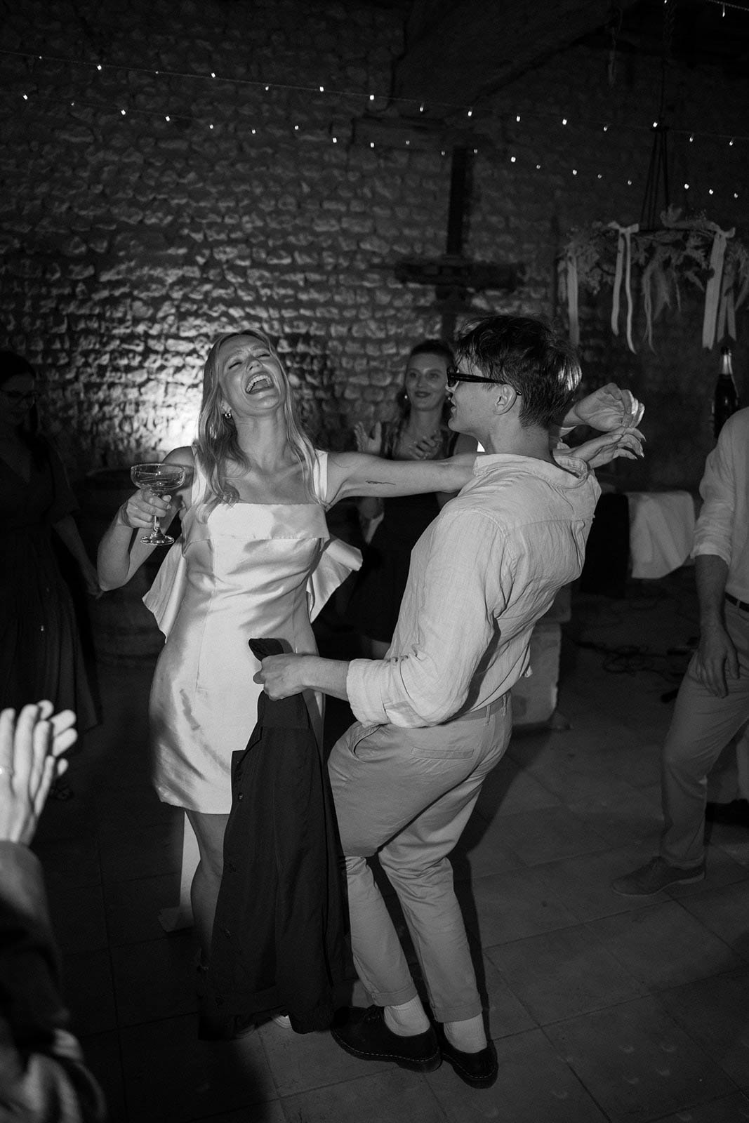 Bride and groom sharing first dance at rustic indoor stone venue with string lights