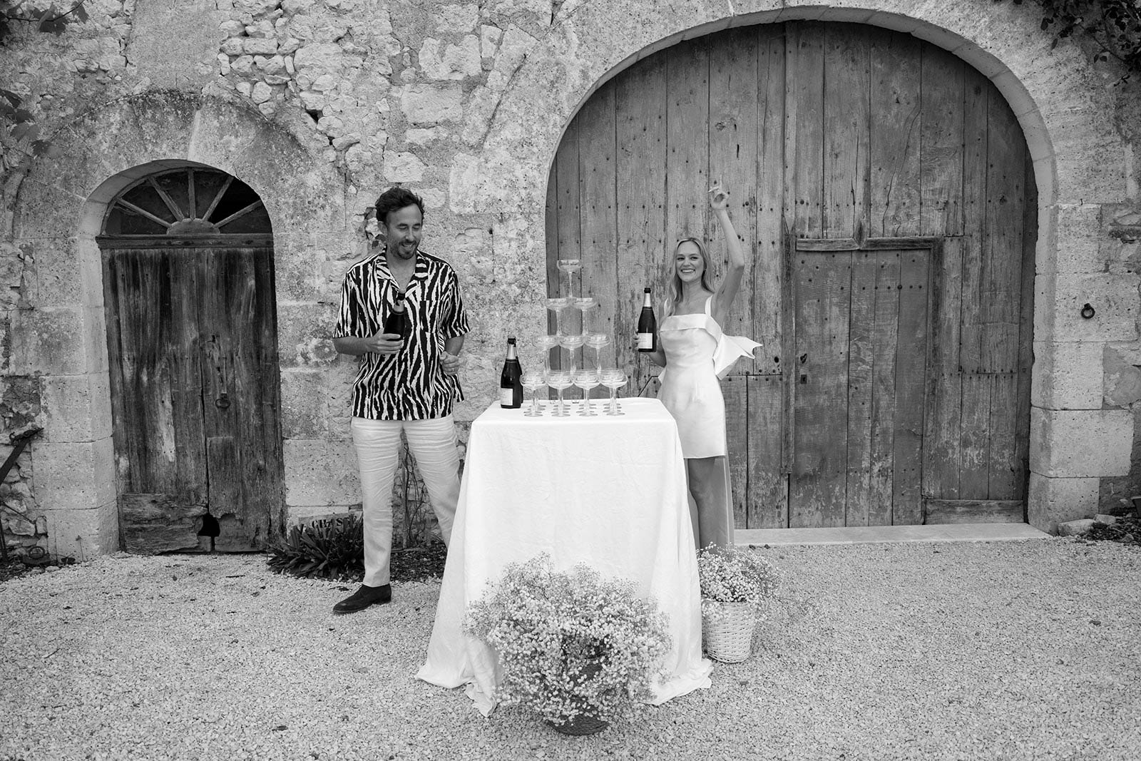 Bride and groom at cocktail hour with champagne tower in stone courtyard