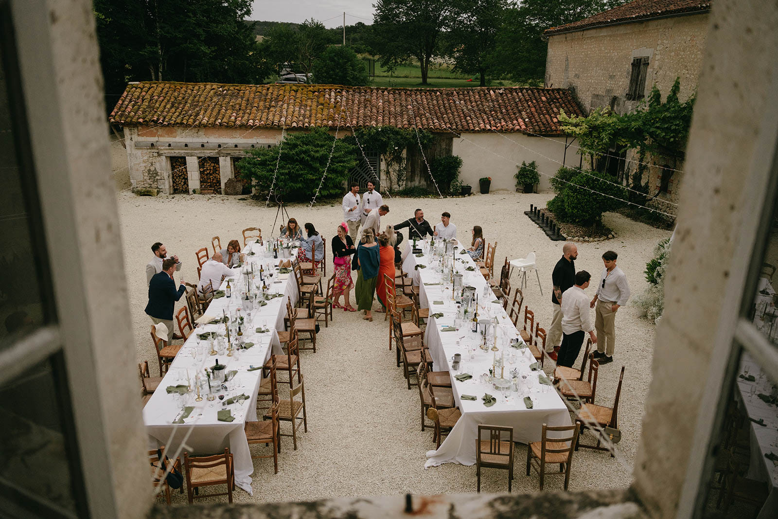 Aerial view of wedding reception in rustic stone courtyard with guests dining at long tables