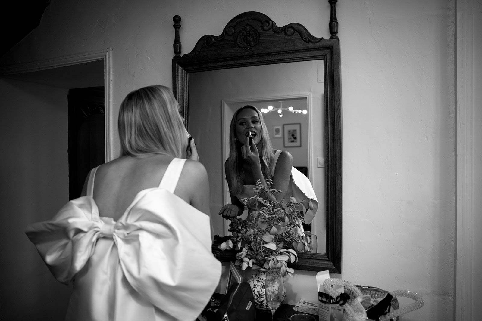 Bride applying makeup in ornate mirror while getting ready in bridal suite