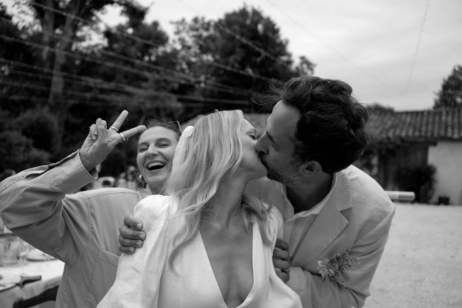 Bride and groom sharing candid moment with child at outdoor countryside wedding venue