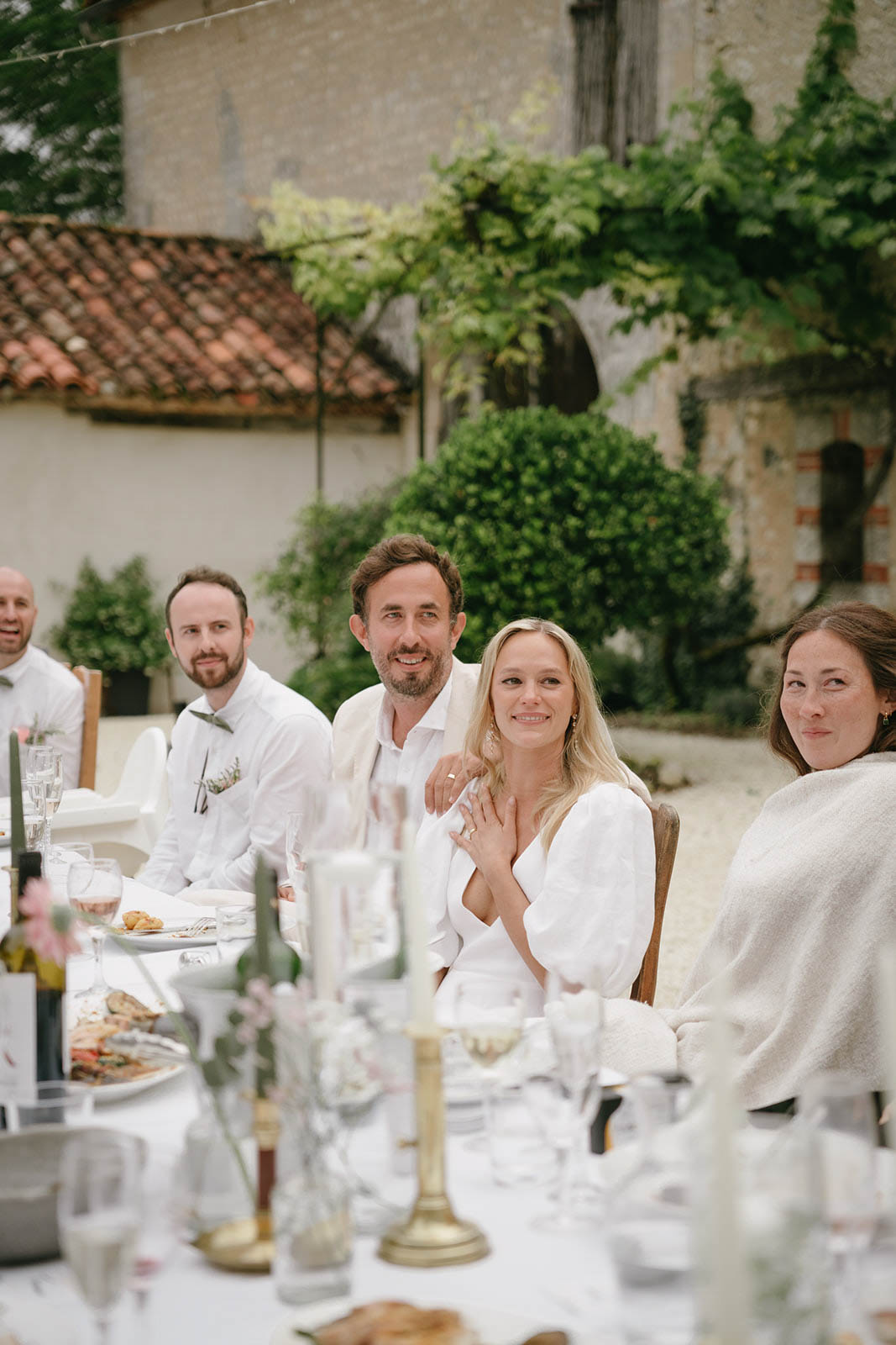Bride and groom dining with guests at outdoor reception table in European stone courtyard
