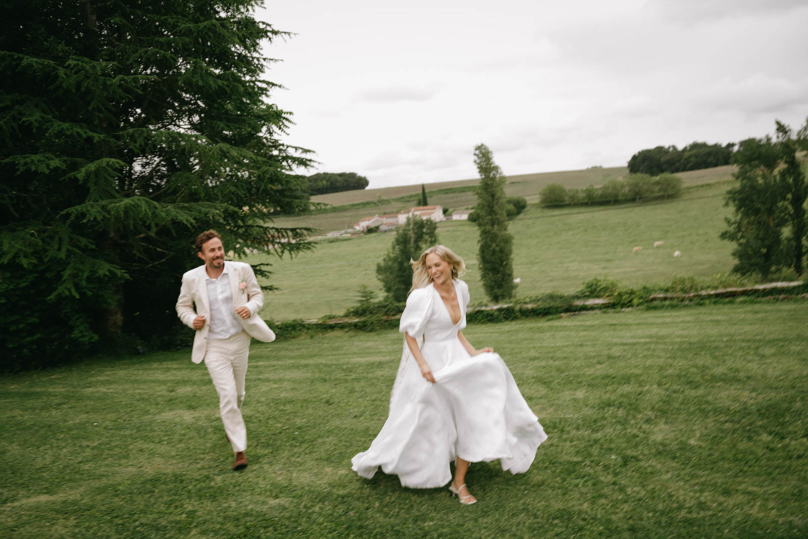 Bride and groom running playfully across countryside field at Mediterranean villa wedding venue