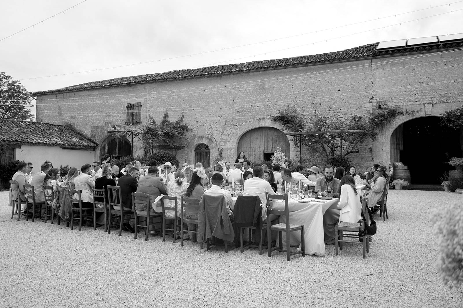 Wedding reception dinner with long banquet table in historic stone courtyard with arched doorways