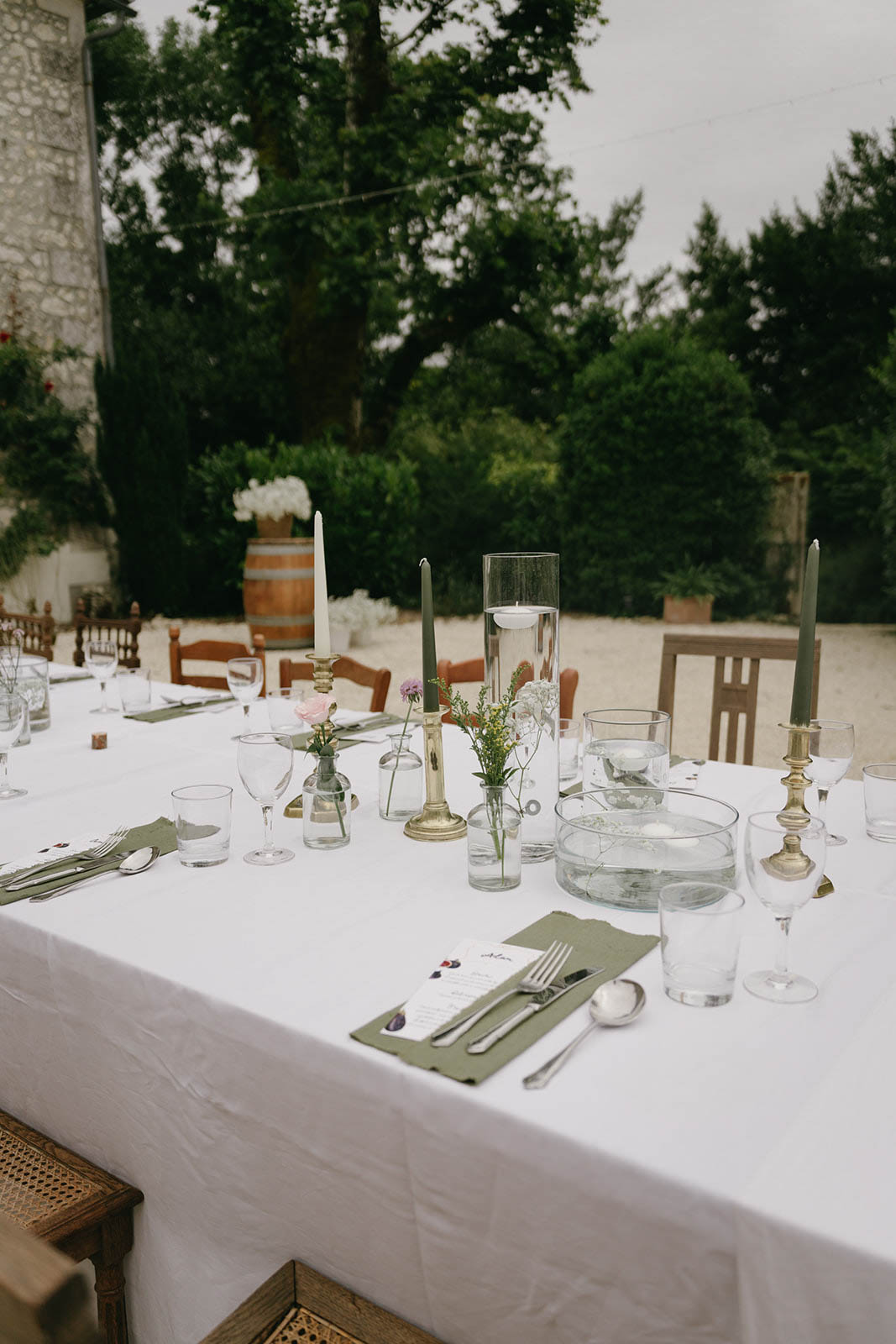 Reception table setting with sage napkins and white florals at outdoor garden wedding venue
