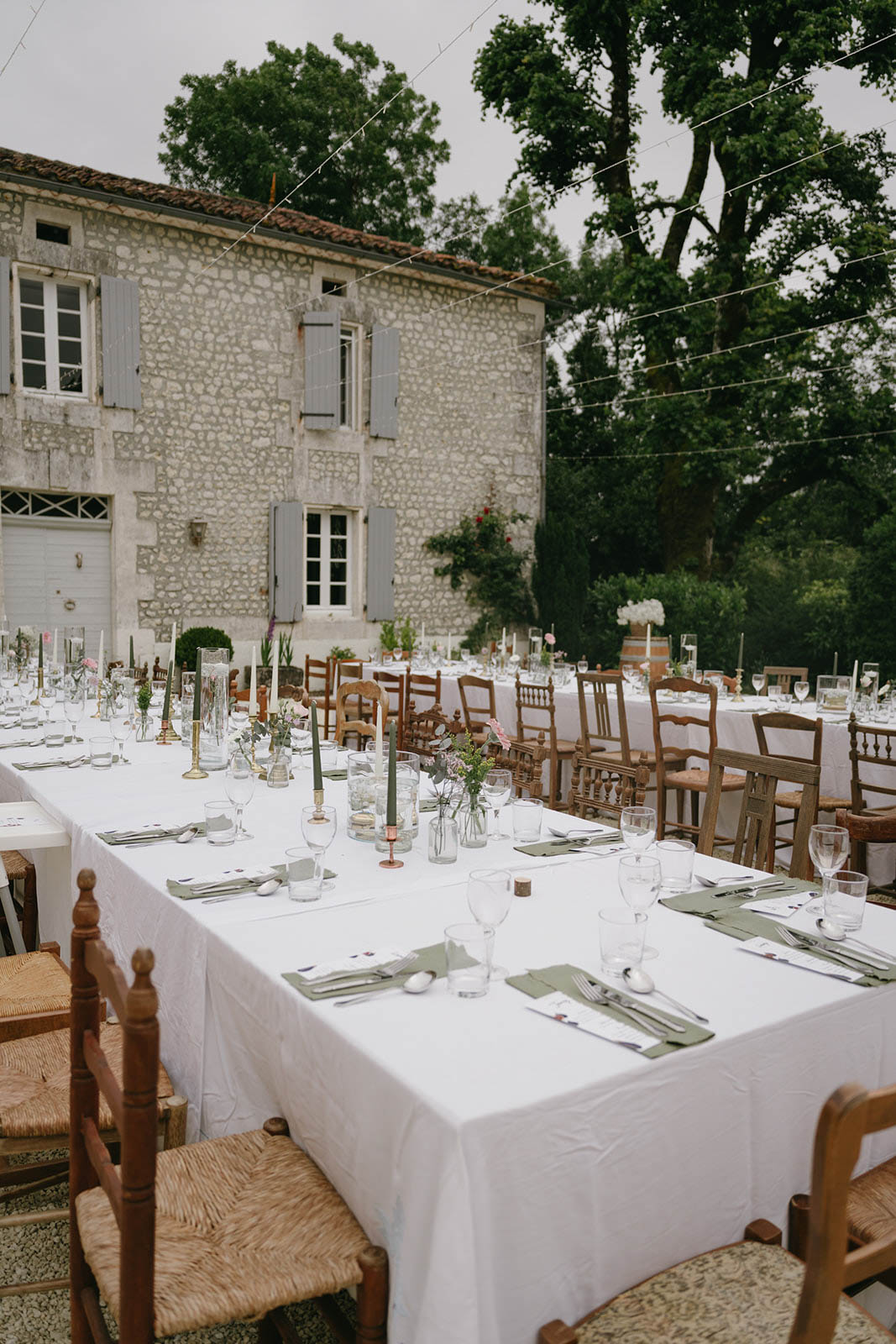 Outdoor reception dinner setup with long tables in French countryside estate courtyard
