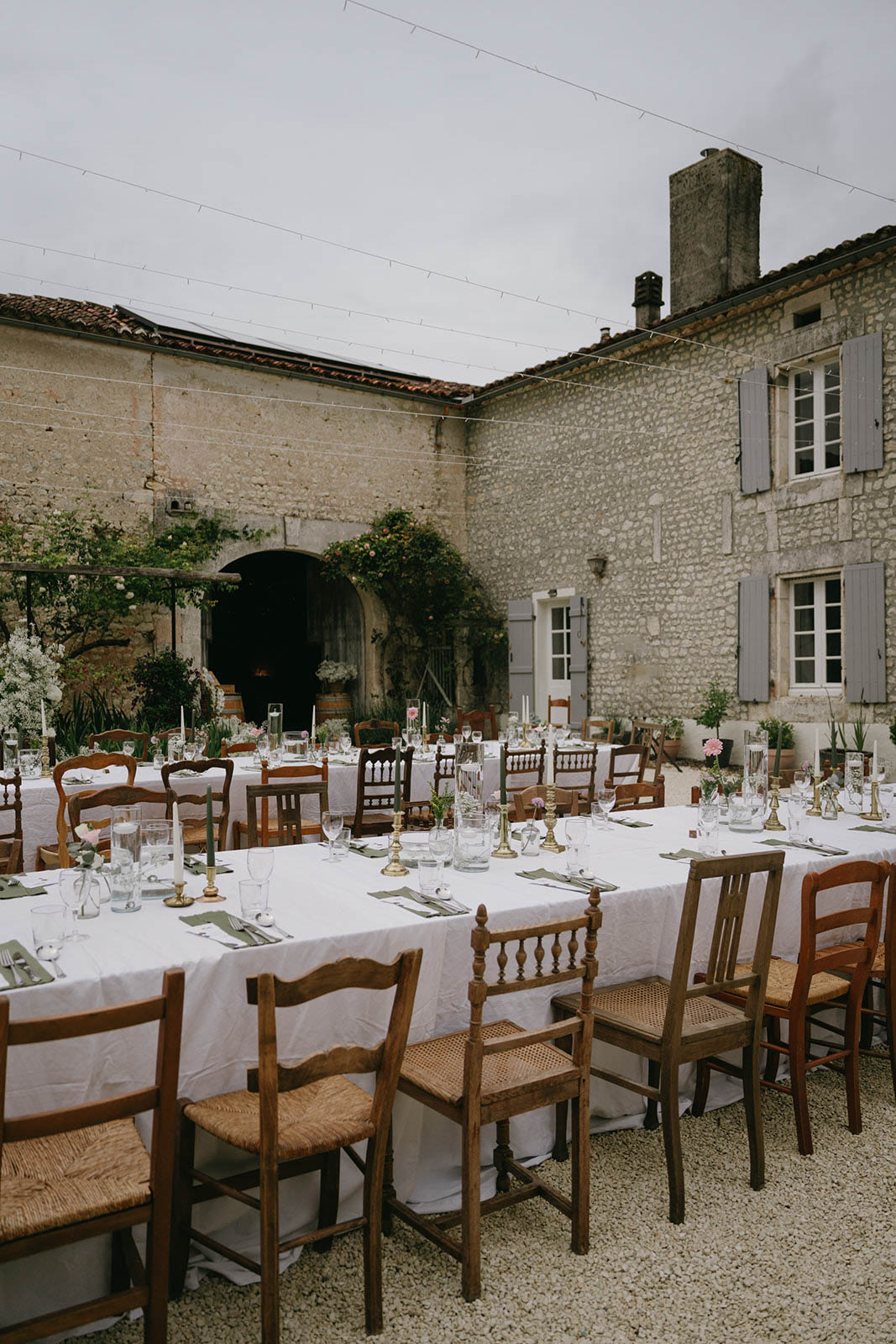 Outdoor wedding reception setup in historic stone courtyard with long tables and string lights