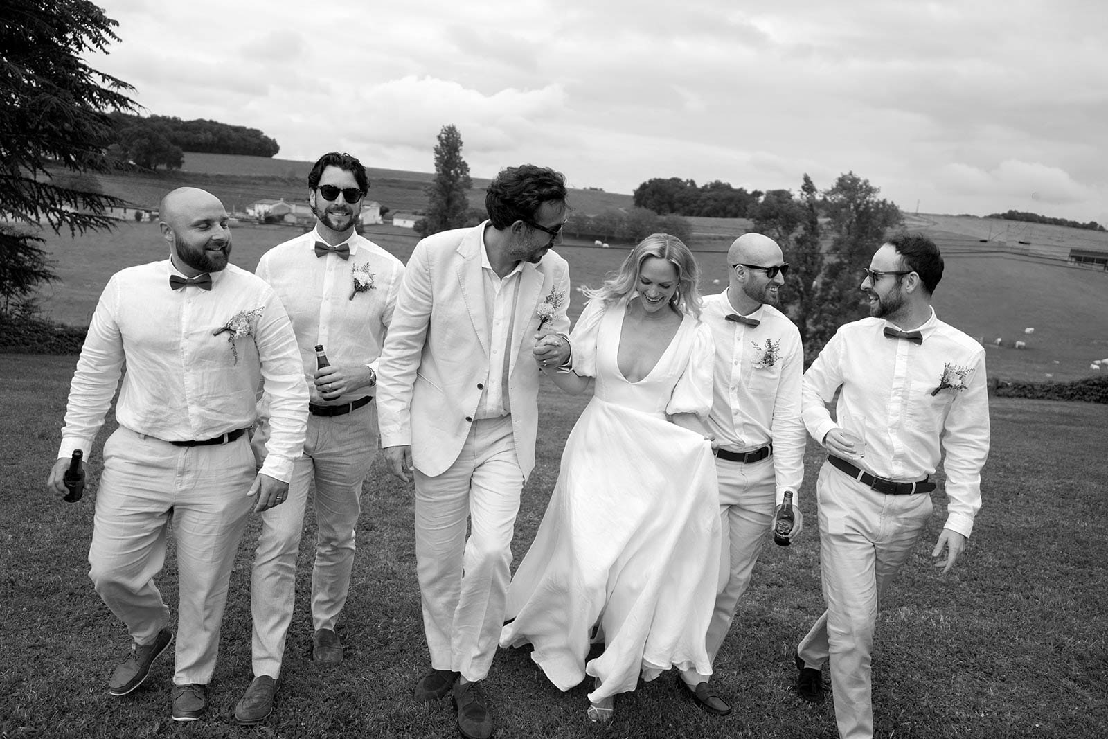 Bridal party walking across open field at rural outdoor wedding venue