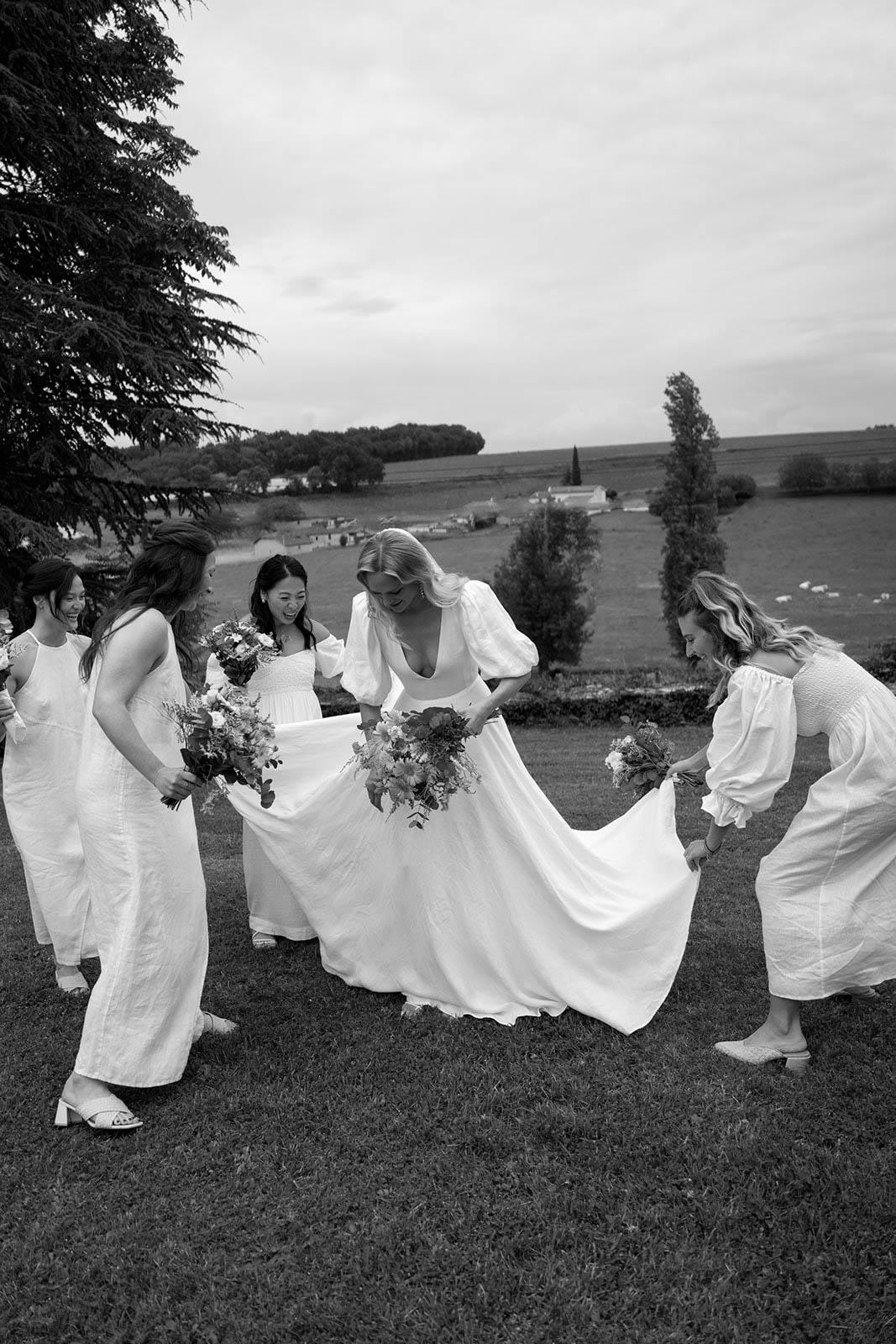 Bridal party portrait with bride and bridesmaids in white dresses in countryside setting
