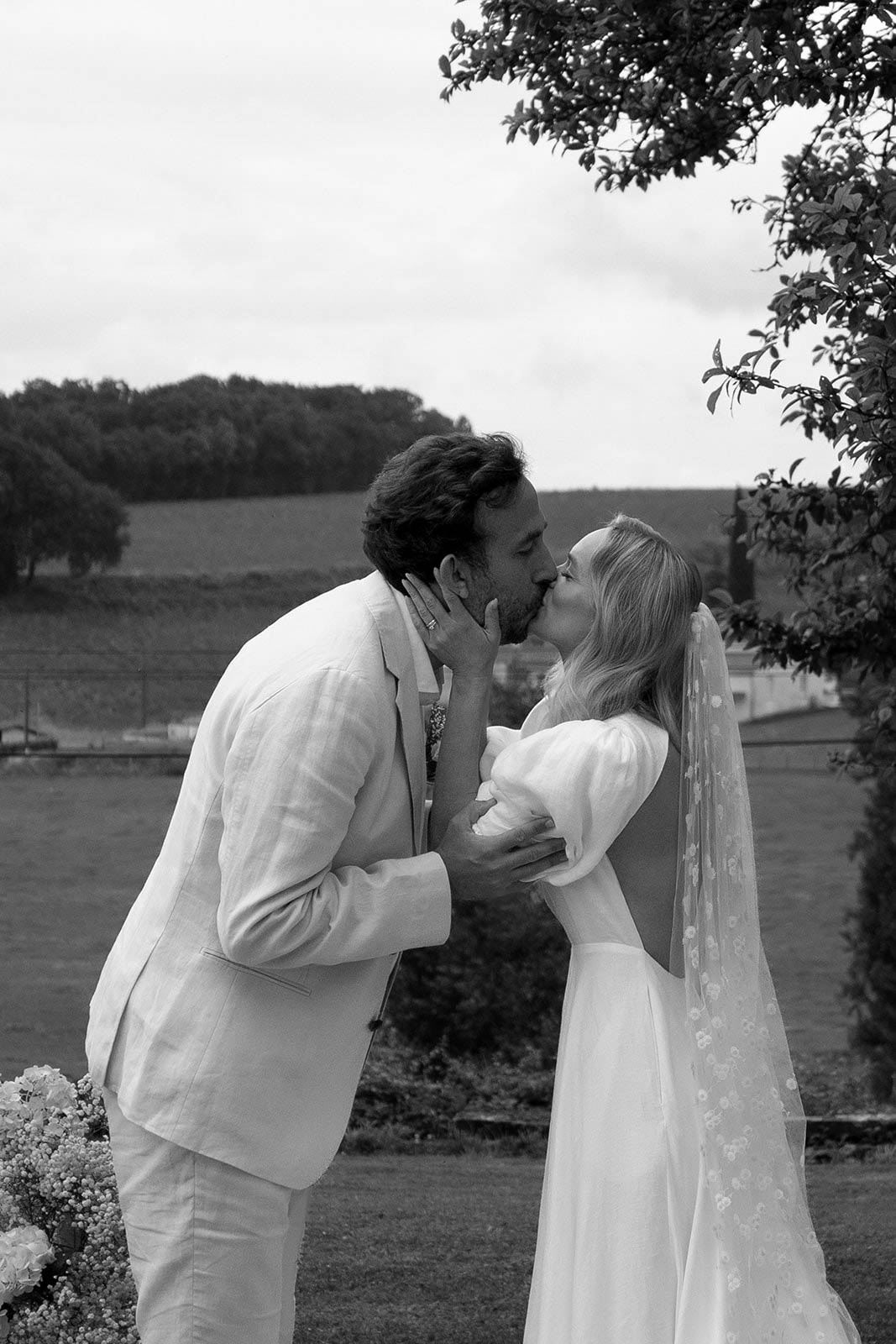Bride and groom kissing outdoors at countryside wedding venue with pastoral landscape background