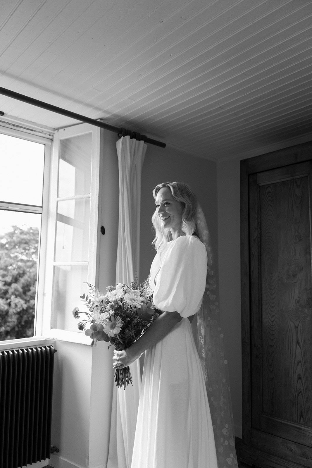 Black and white bridal portrait by window in modern bridal suite with exposed beams
