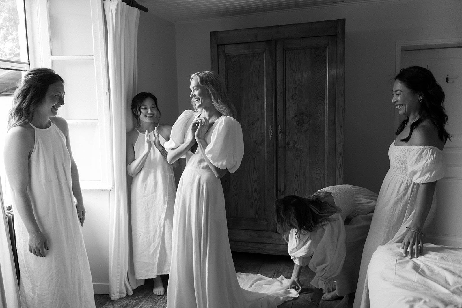 Bride and bridal party getting ready moment in indoor bedroom with natural window light