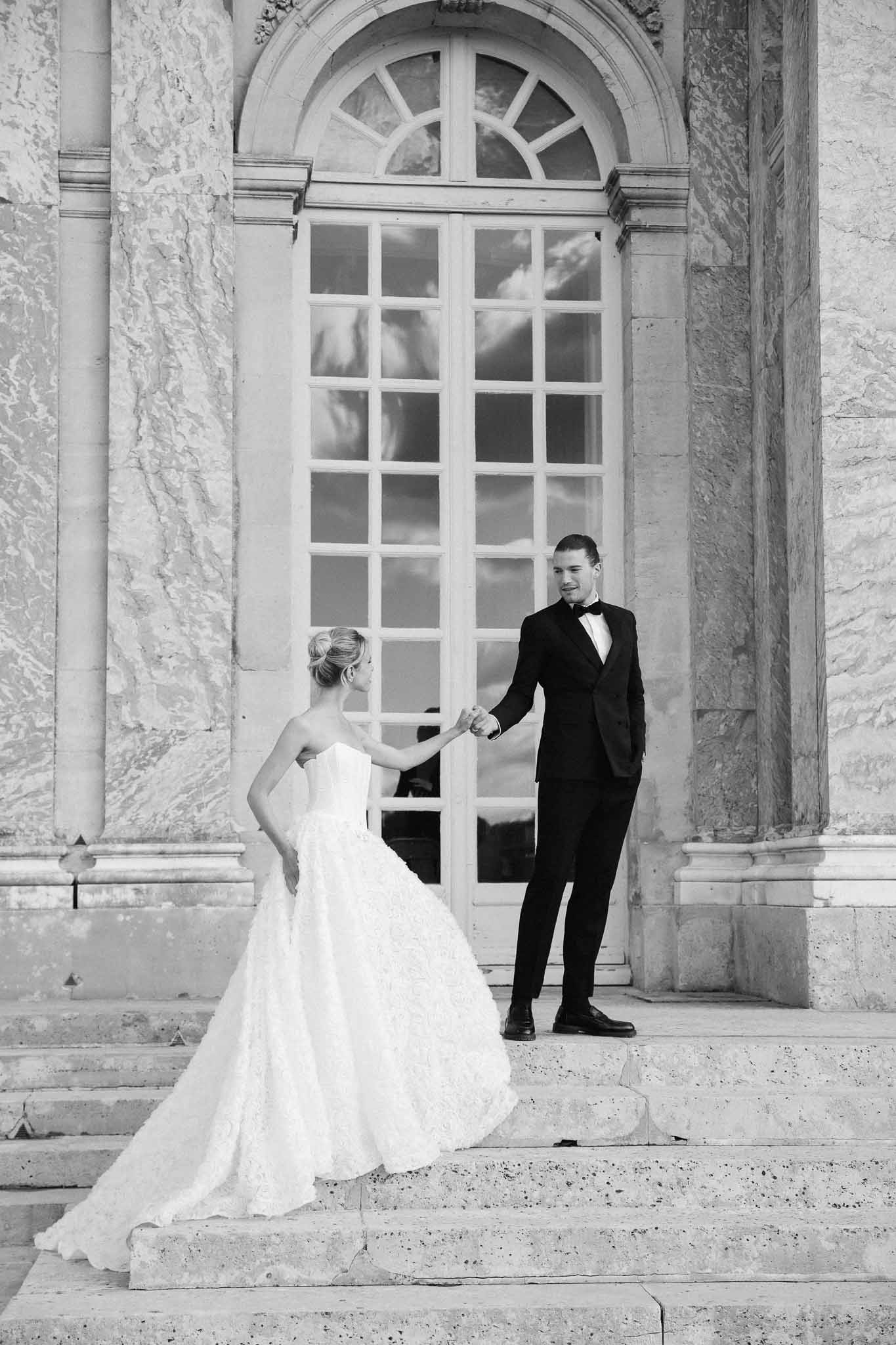 Bride and groom holding hands on classical stone building steps with neoclassical columns