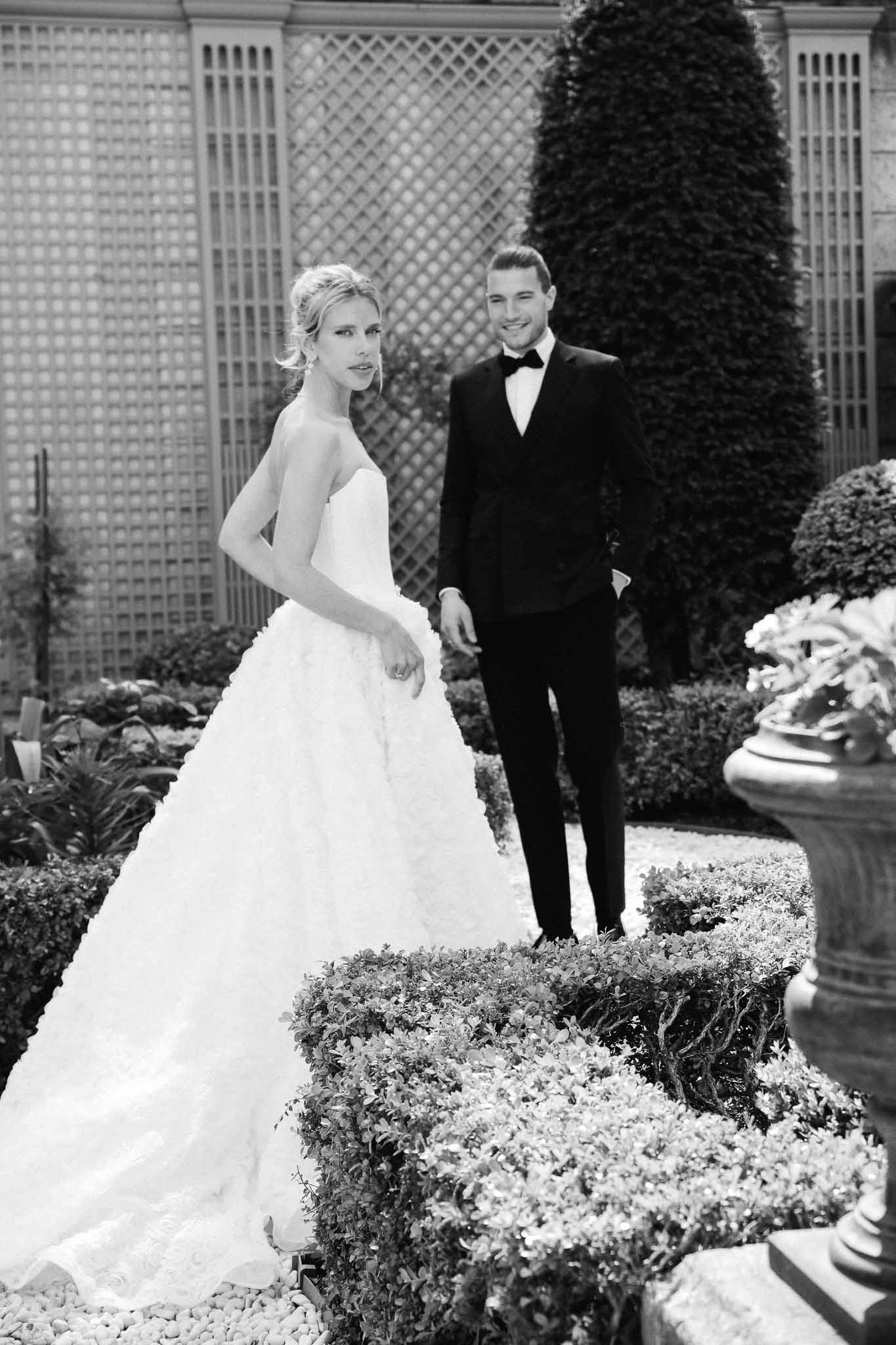 Bride and groom formal portrait in manicured courtyard garden with geometric lattice panels