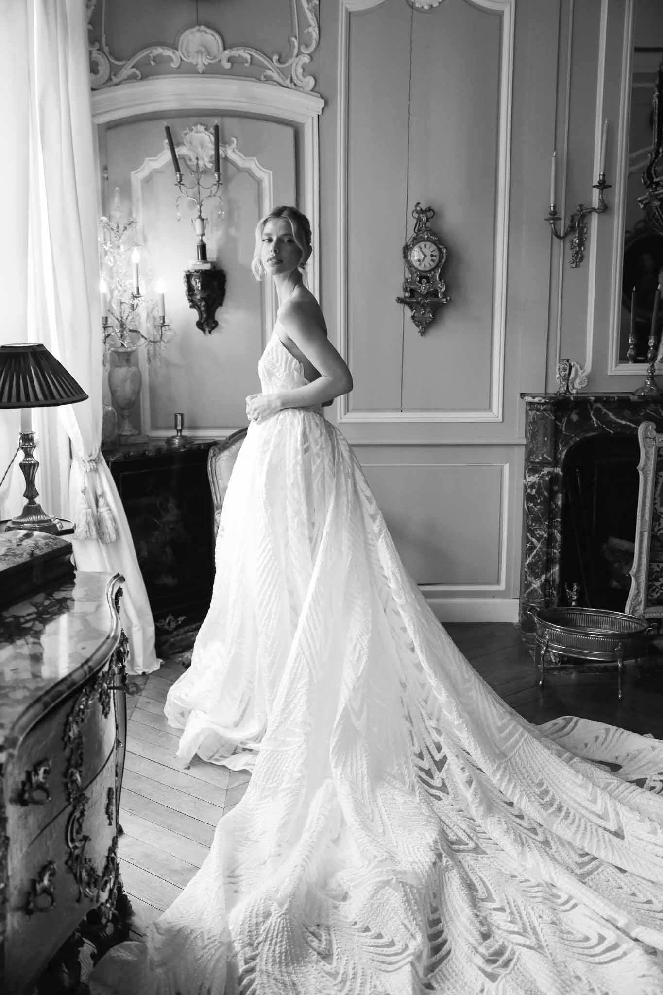 Bride in wedding dress with geometric train in classical Parisian interior with ornate paneling and fireplace