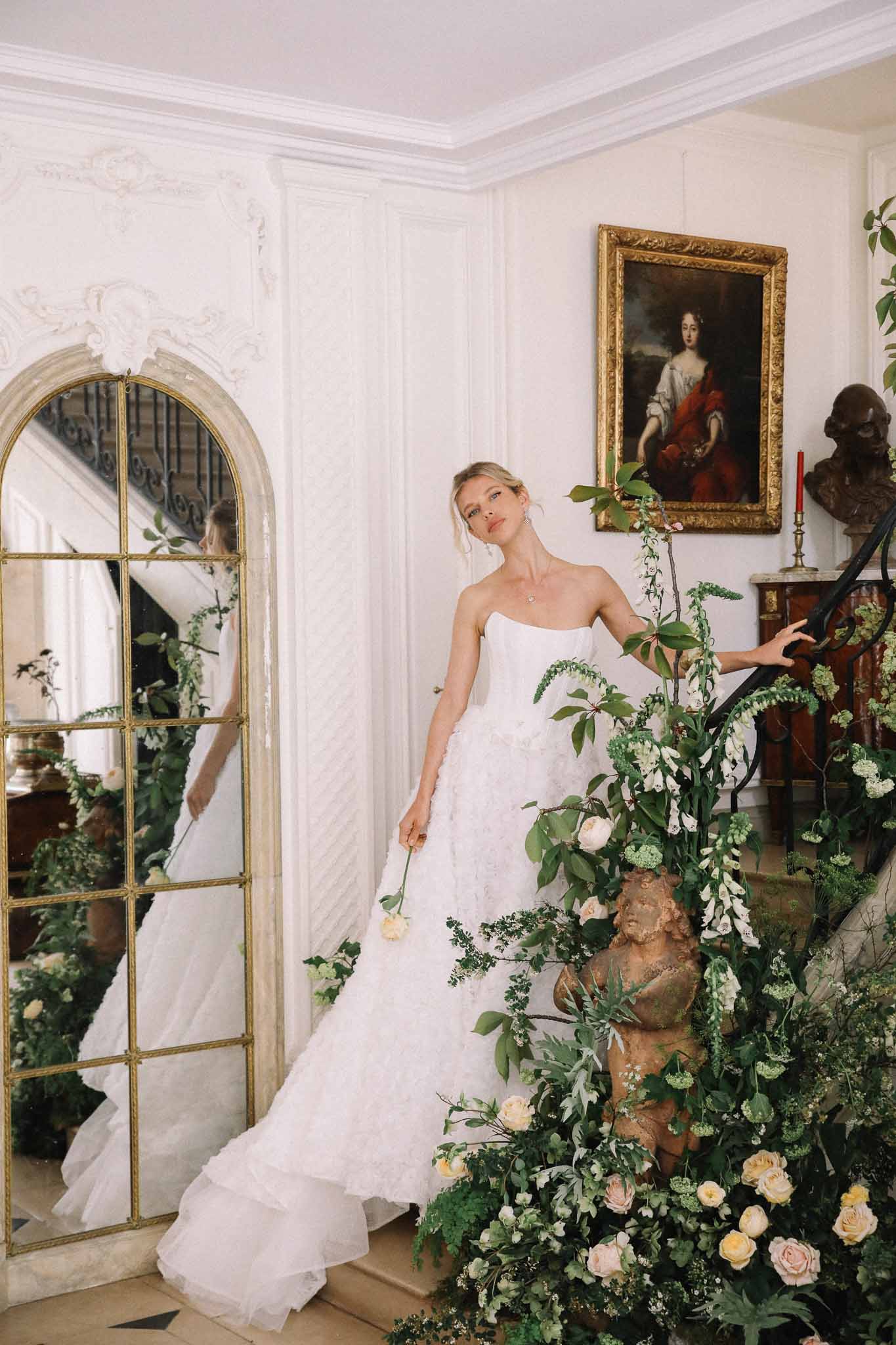 Bride in strapless white gown with train in classical European salon with ornate decor and floral arrangements