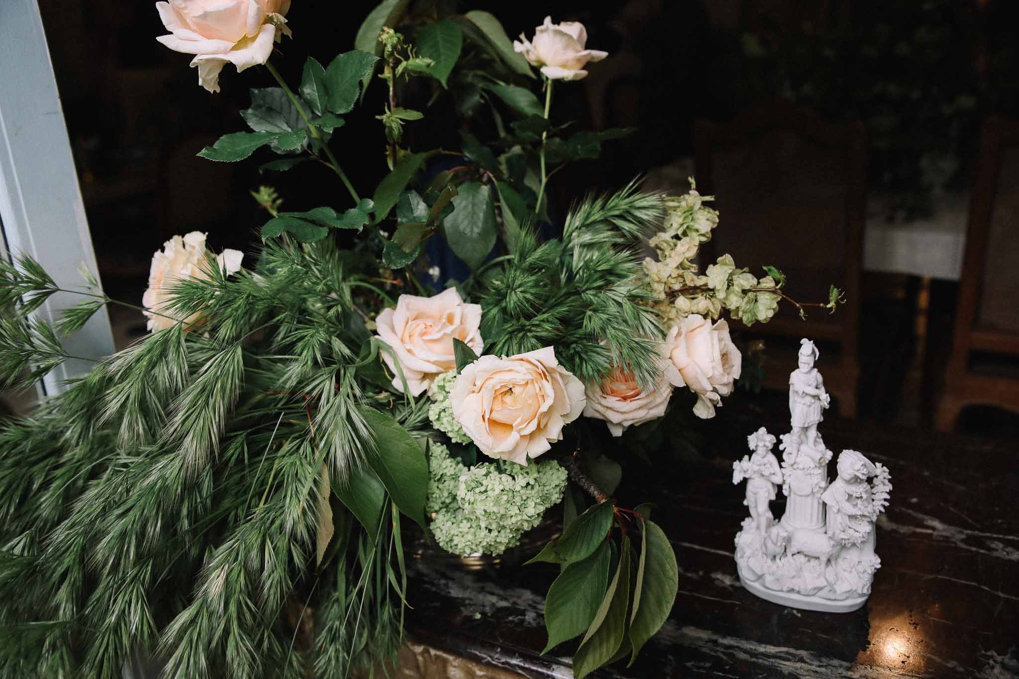 Blush garden rose centerpiece with white porcelain figurine on reception table