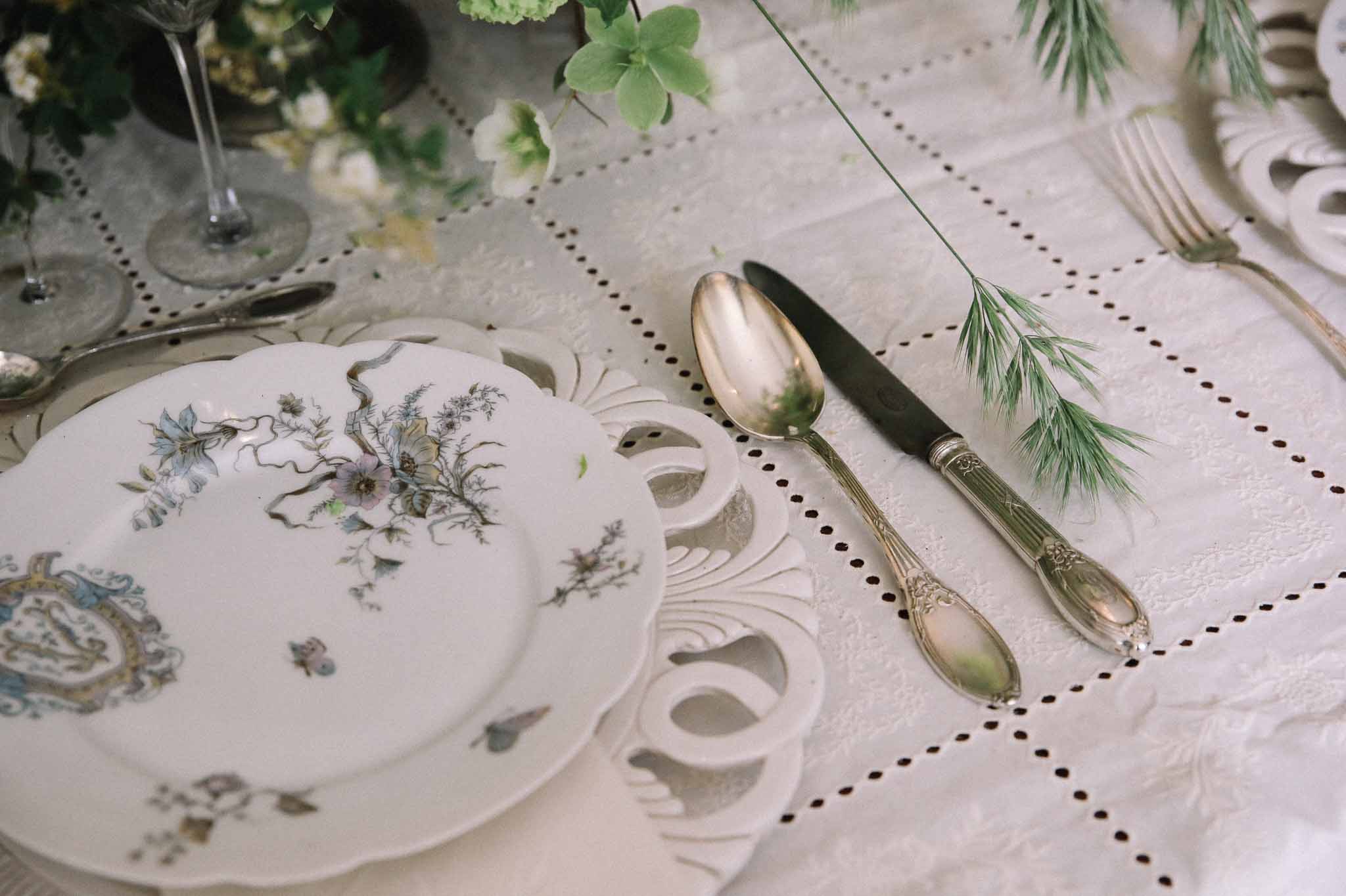 Elegant botanical place setting with painted plates and greenery at wedding reception