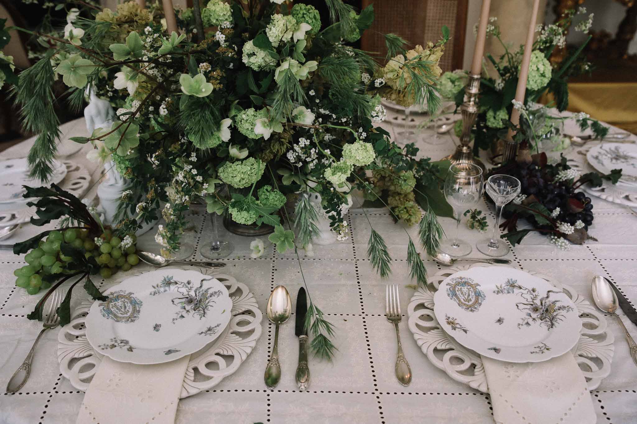 Elegant table setting with botanical porcelain plates and green and white floral centerpiece at wedding reception