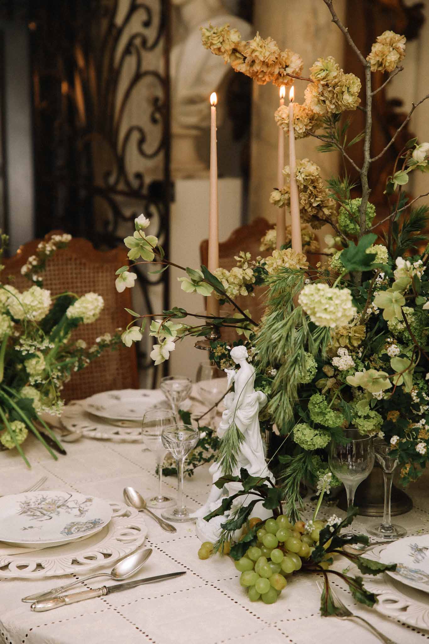 Formal reception table setting with peach candles and garden-style florals at classical venue