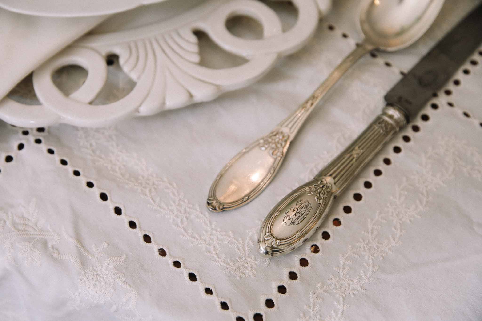 Ornate silverware and napkin ring on ivory linen at formal wedding reception table setting