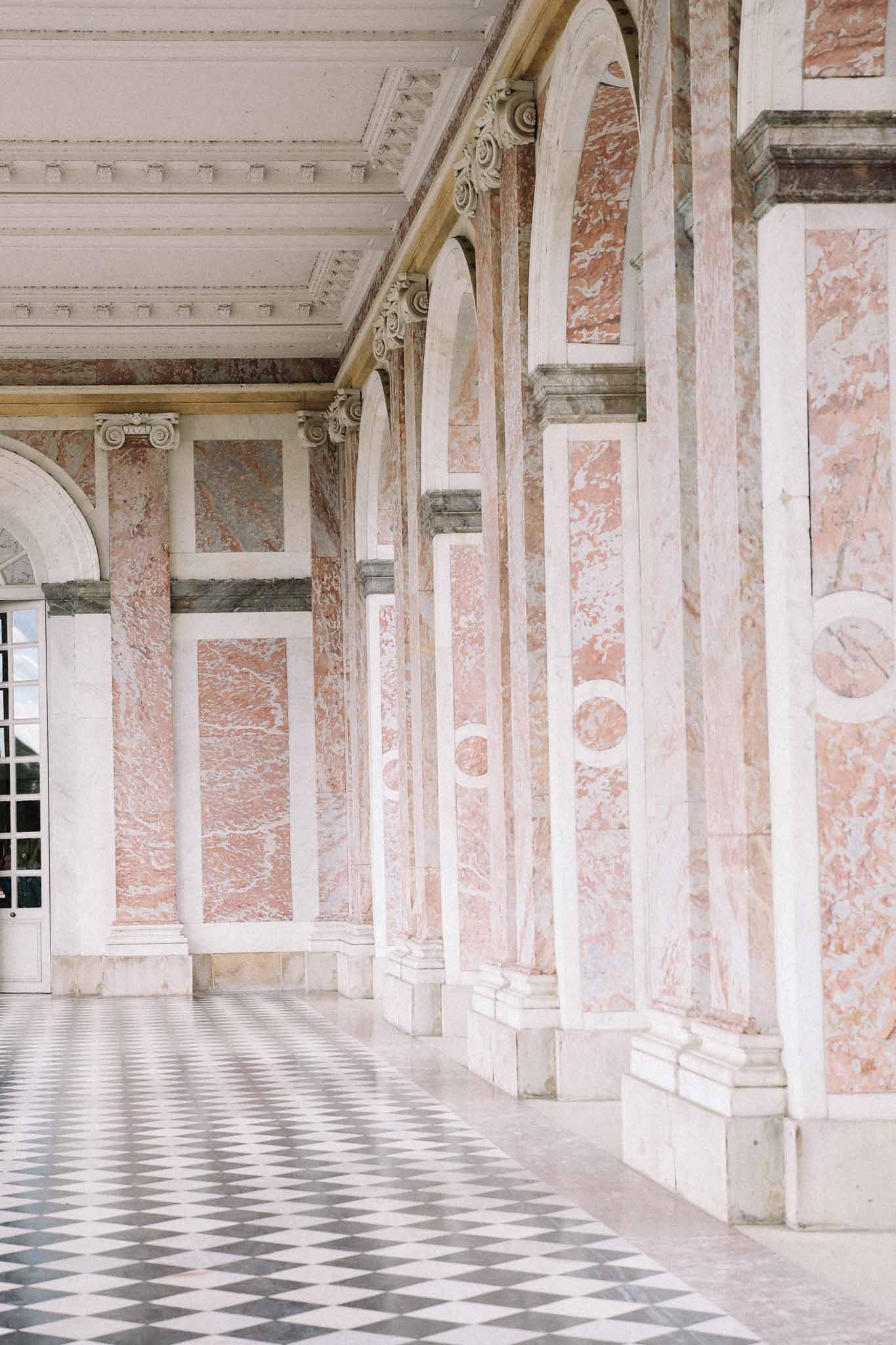 Classical covered corridor with Corinthian columns and ornate ceiling at elegant wedding venue