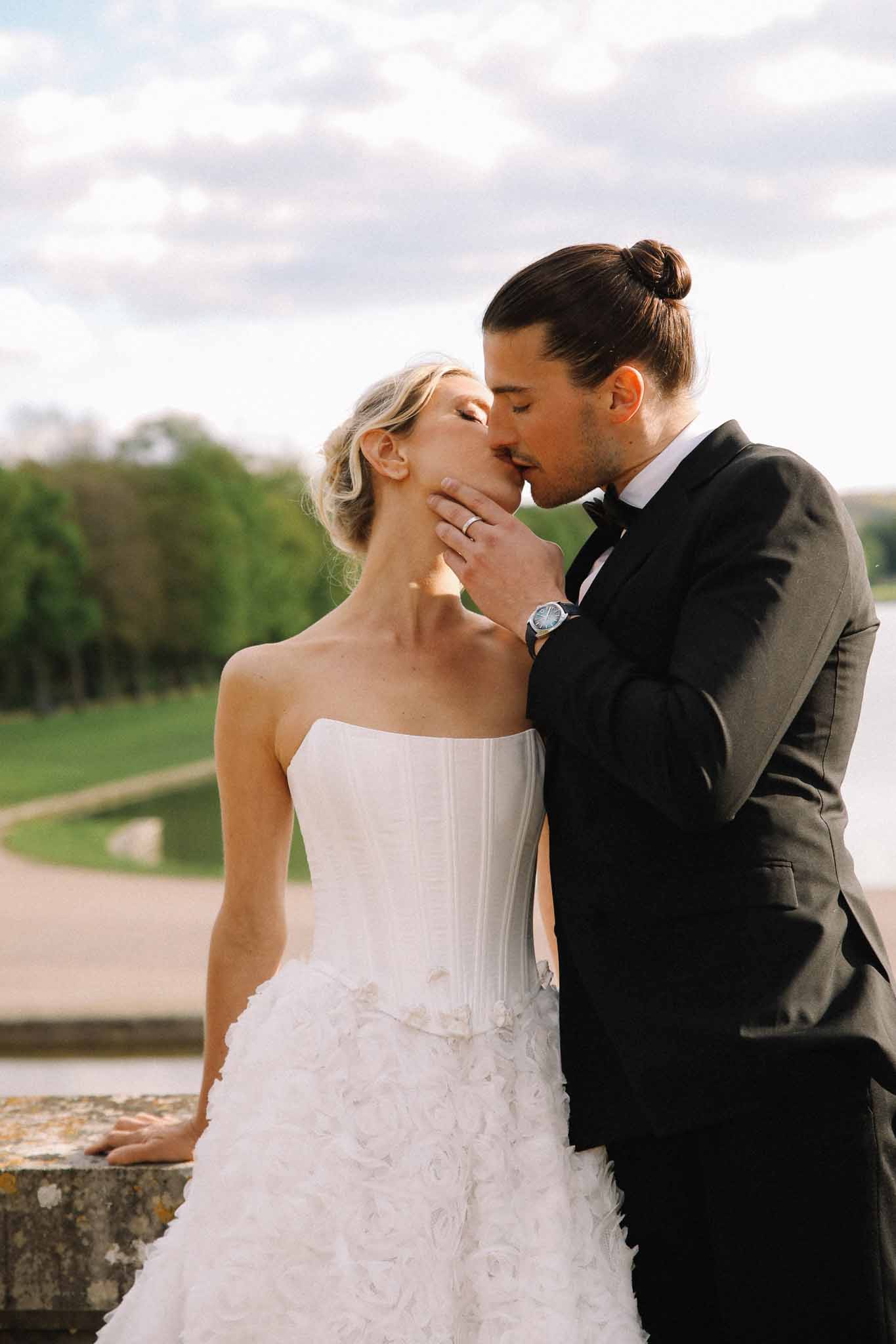 Bride and groom kissing during outdoor portrait session overlooking countryside grounds
